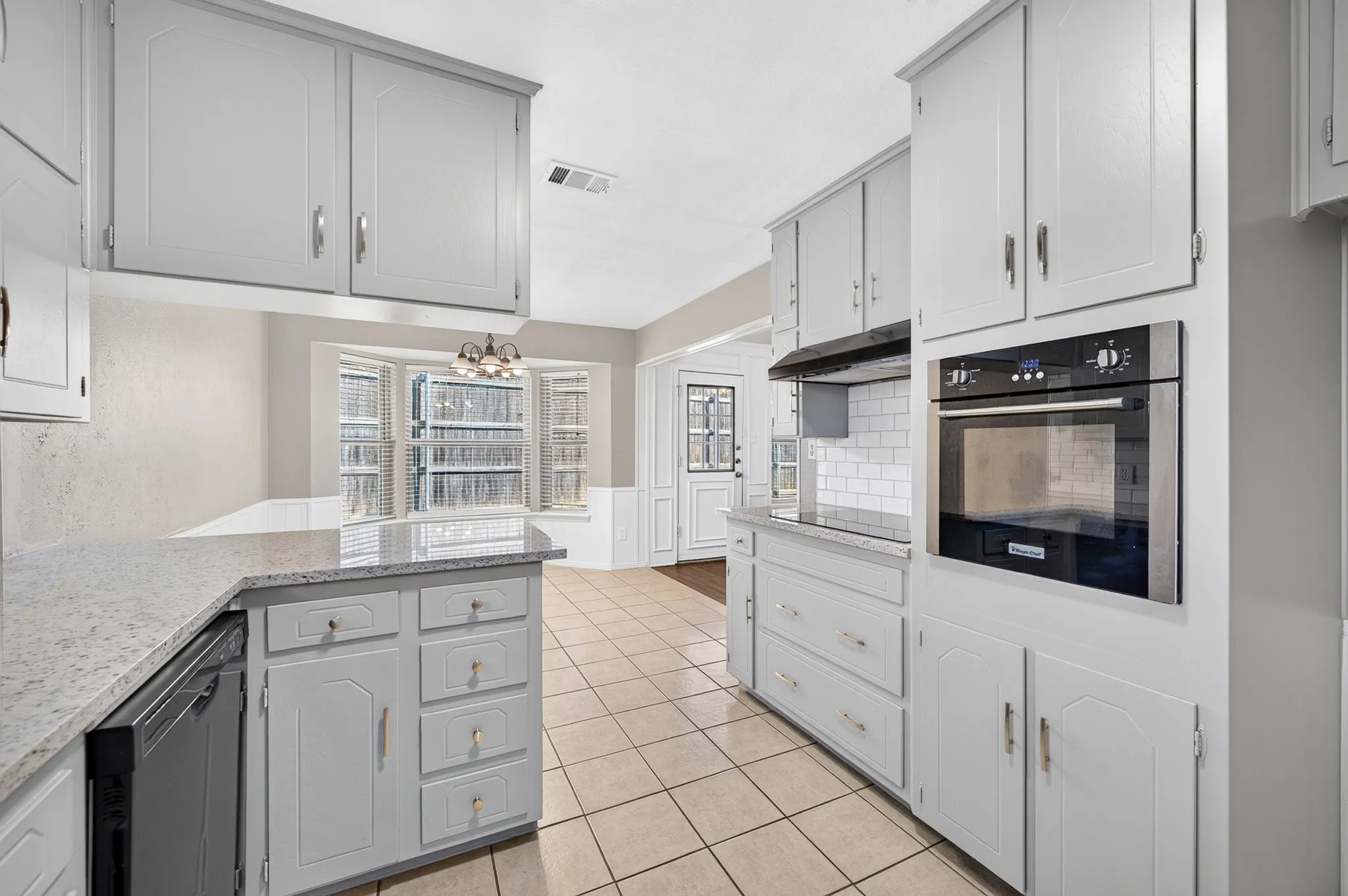 Kitchen featuring light-toned cabinetry, granite-style countertops, an integrated wall oven, subway tile backsplash, and tile flooring