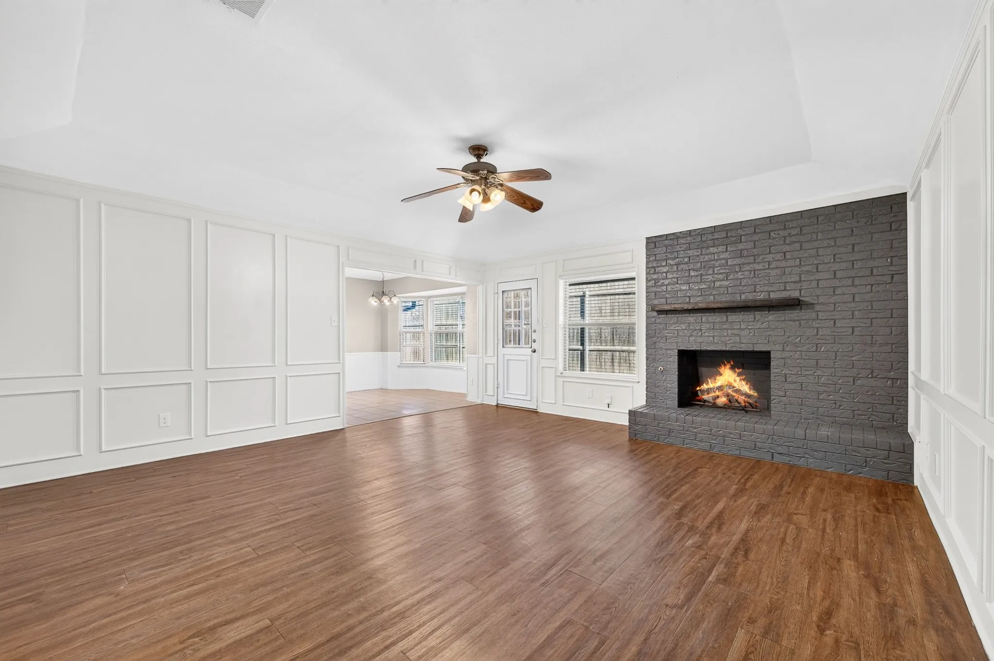 Spacious room featuring wood-finish flooring, a tray ceiling, and a ceiling fan