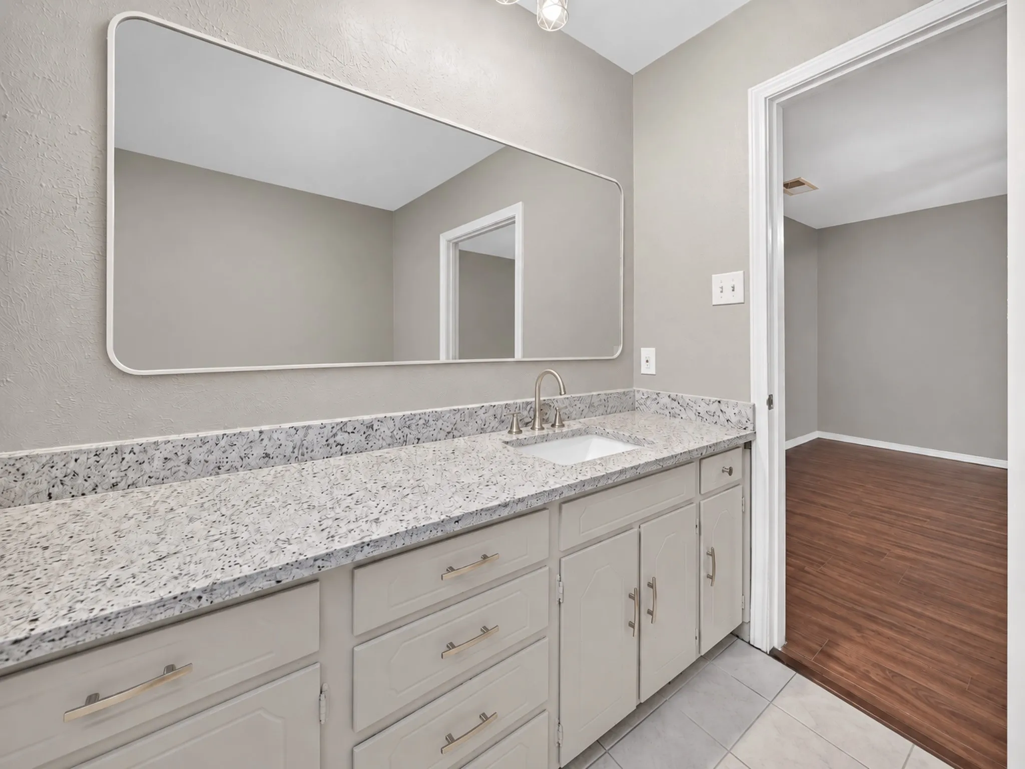 Spacious vanity with light-toned cabinetry, a built-in sink, and a speckled countertop