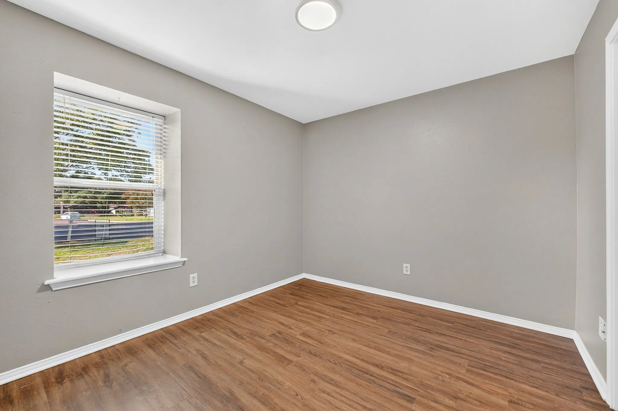 Neutral-toned walls, wood-finish flooring, and a window with blinds