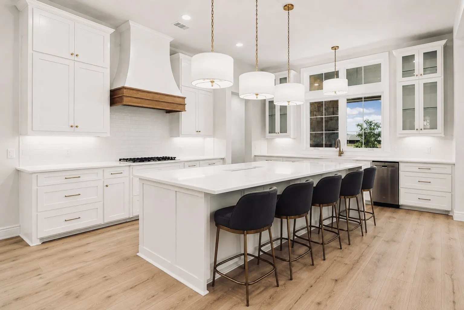Spacious kitchen featuring an expansive island, white cabinetry, integrated stainless steel appliances, a wood-finish range hood, and wood-finish flooring