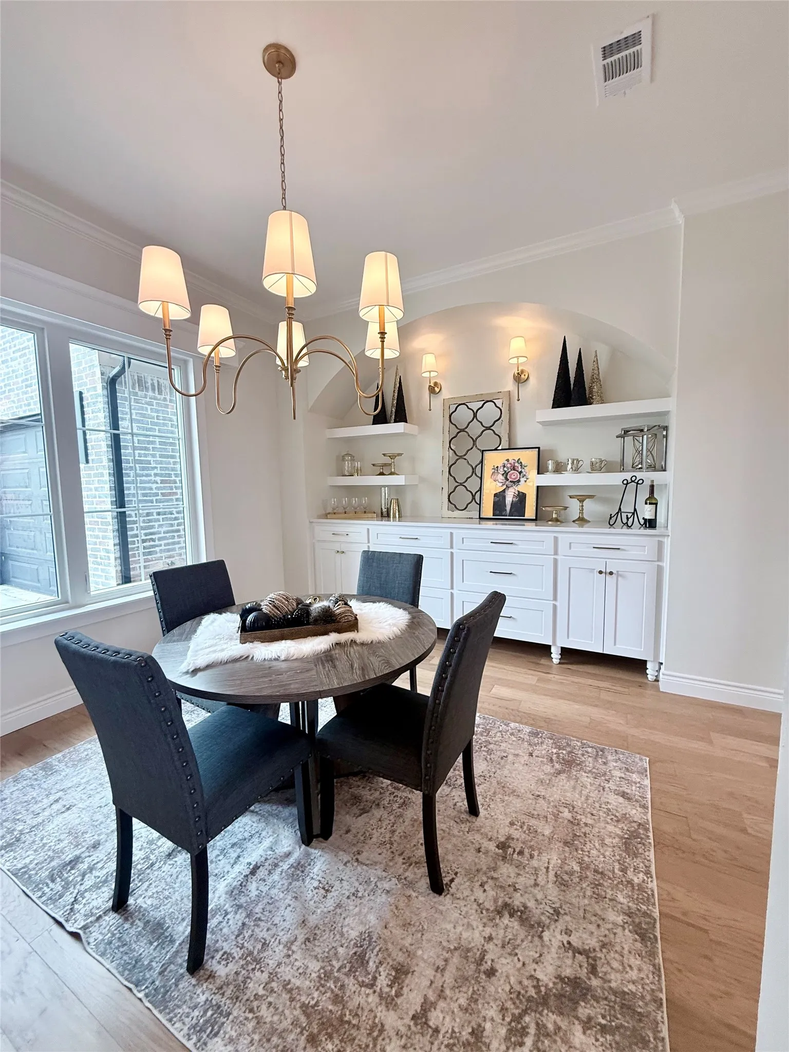 Built-in cabinetry with open shelving, arched alcove, crown molding, and wood-finish flooring