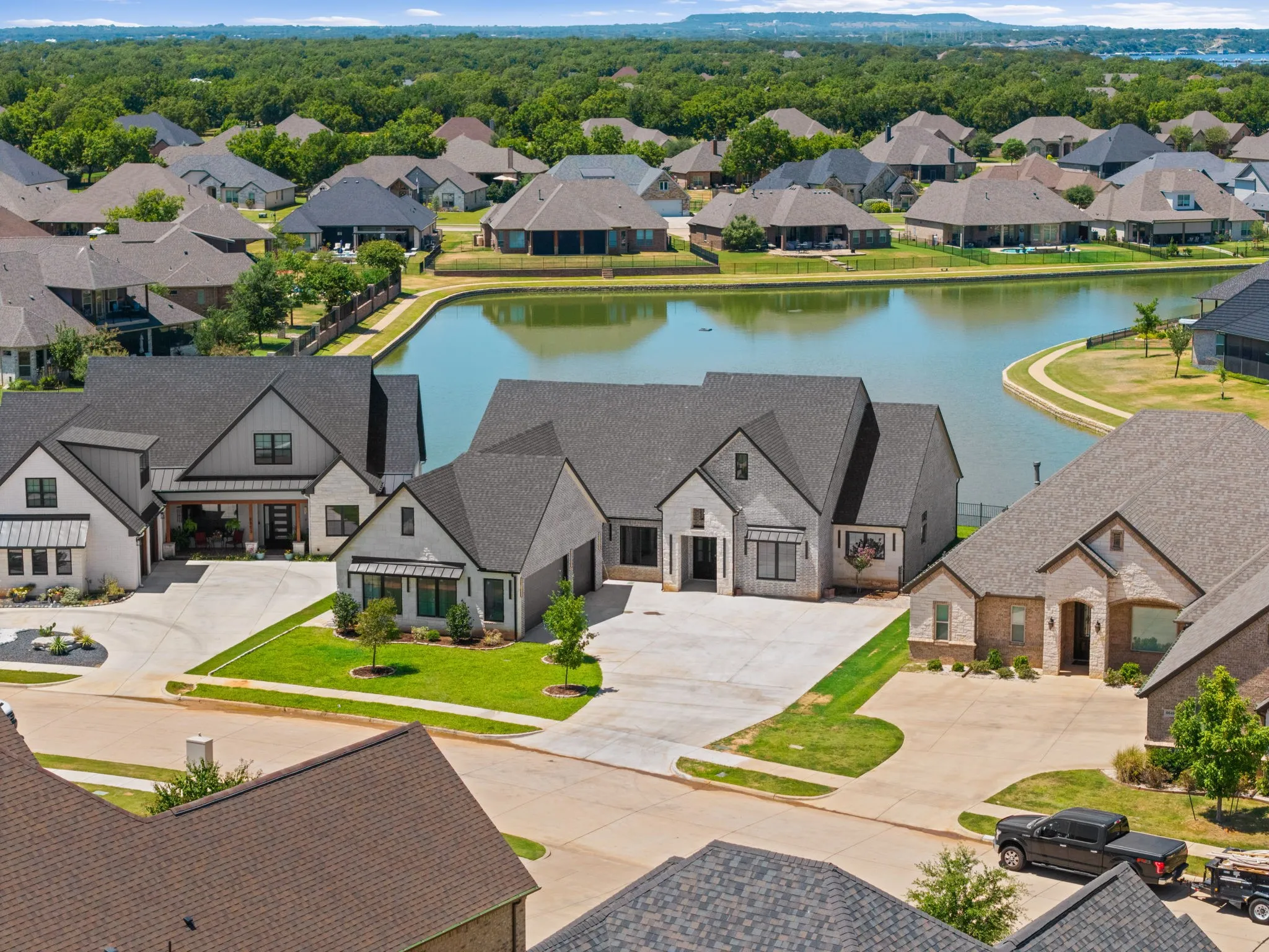 Modern farmhouse architectural style, asphalt shingle roofing, attached garage, concrete driveway, and a manicured lawn