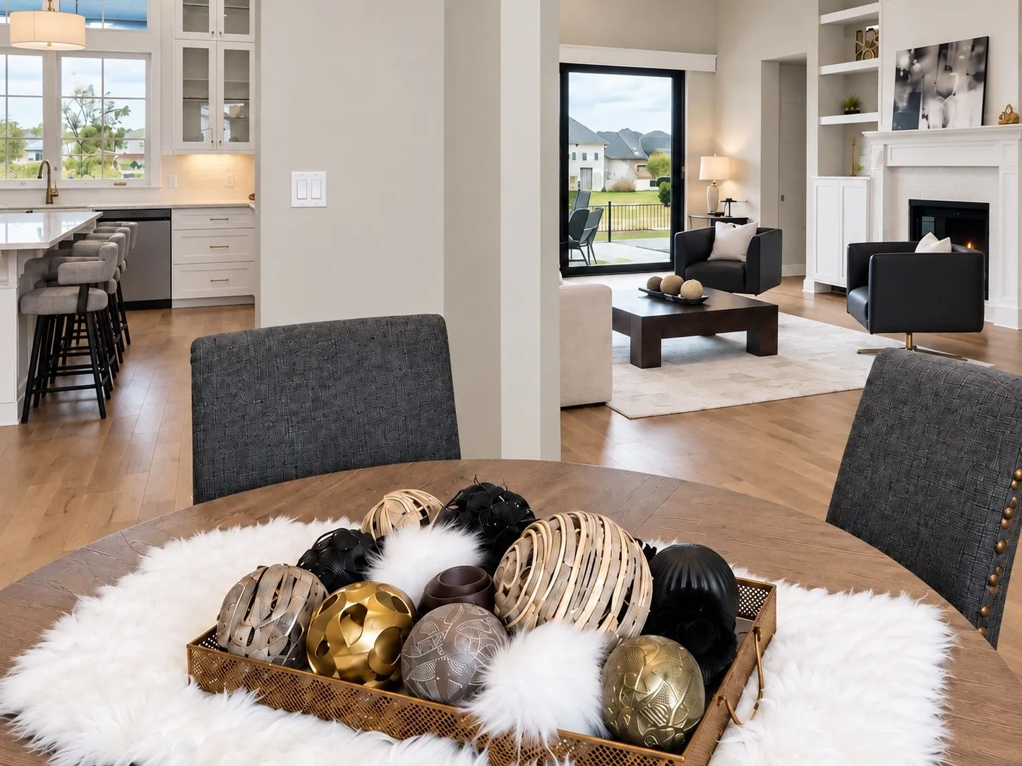 Hardwood-finish flooring throughout, living area with fireplace and built-in shelving, kitchen with white cabinetry and island seating, and a sliding glass door to exterior