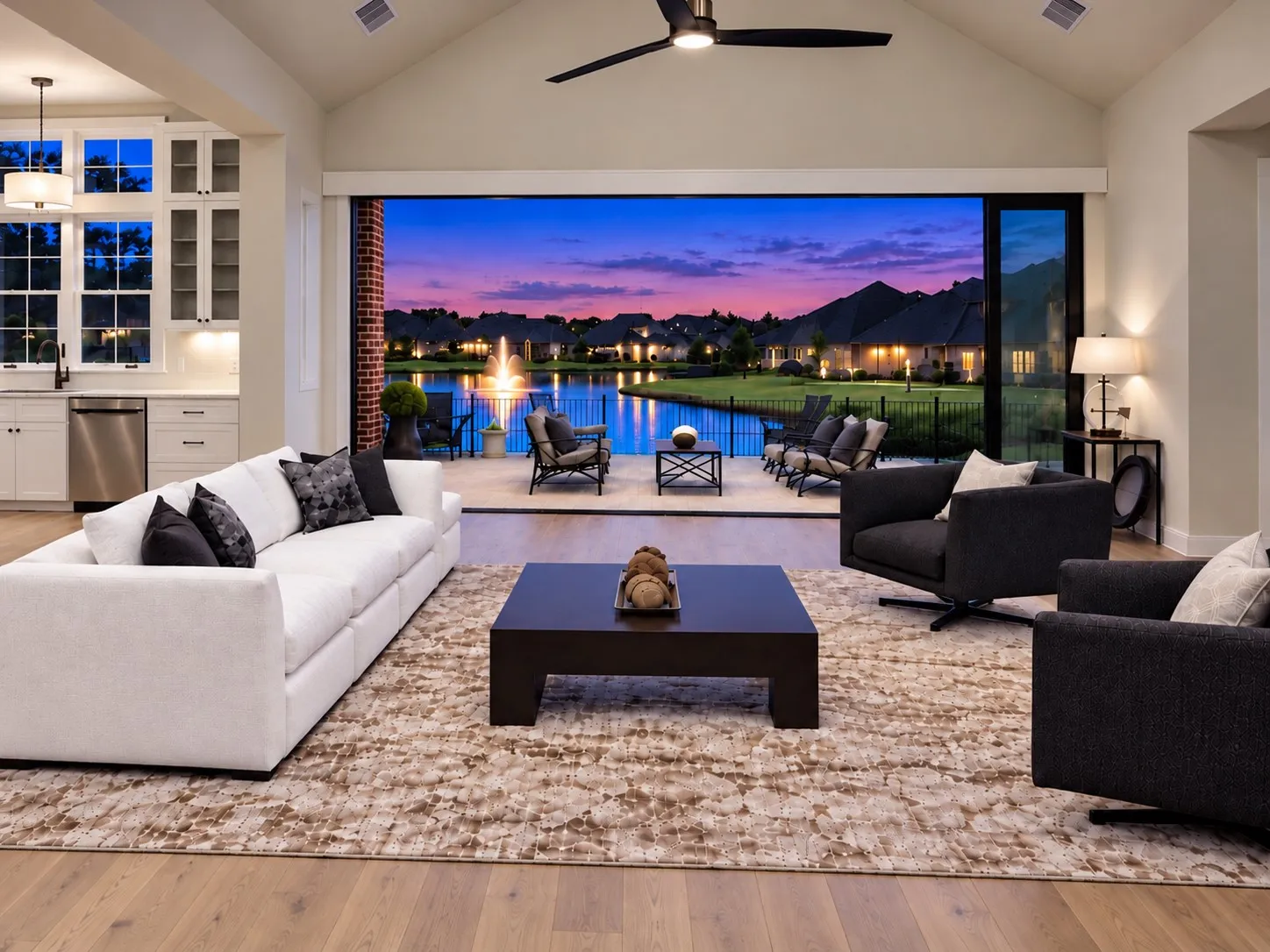 Vaulted ceiling with an installed ceiling fan, wood-finish flooring, and a full wall of sliding glass panels opening to an outdoor patio with a water feature