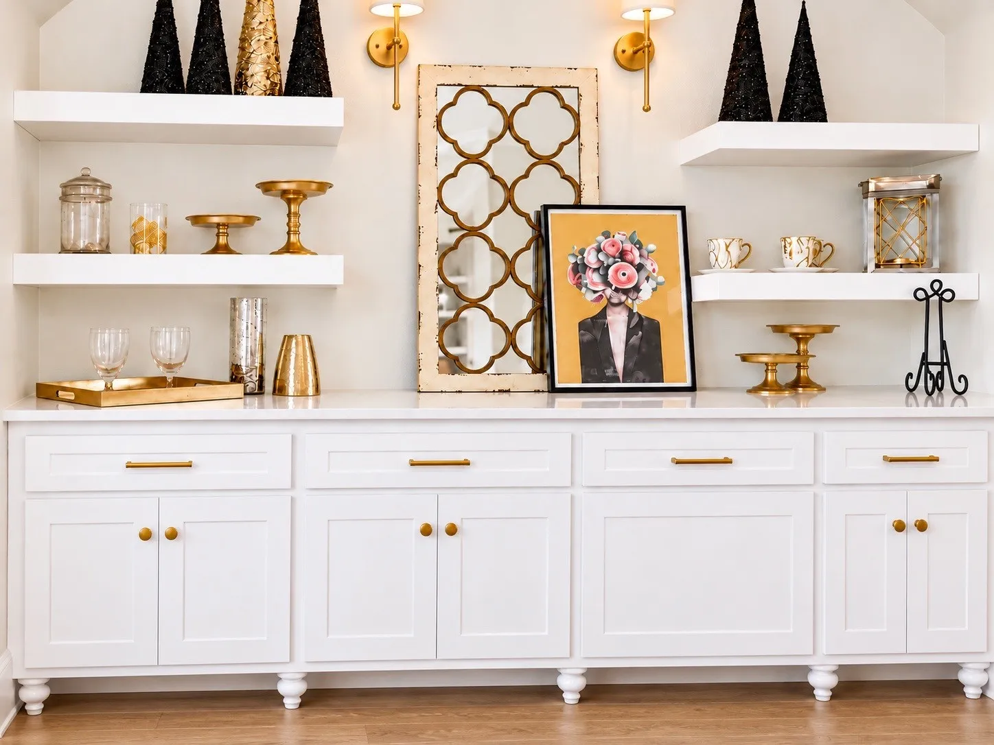 Built-in white cabinetry with gold-tone hardware, floating shelves, and a light-toned countertop