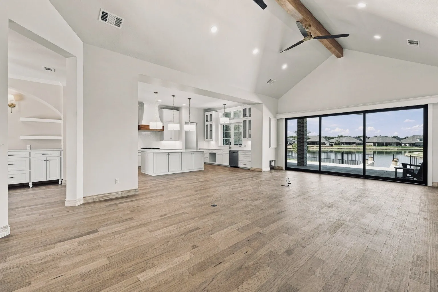 Vaulted ceiling with exposed beam, wood-finish flooring, recessed lighting, and expansive sliding glass doors