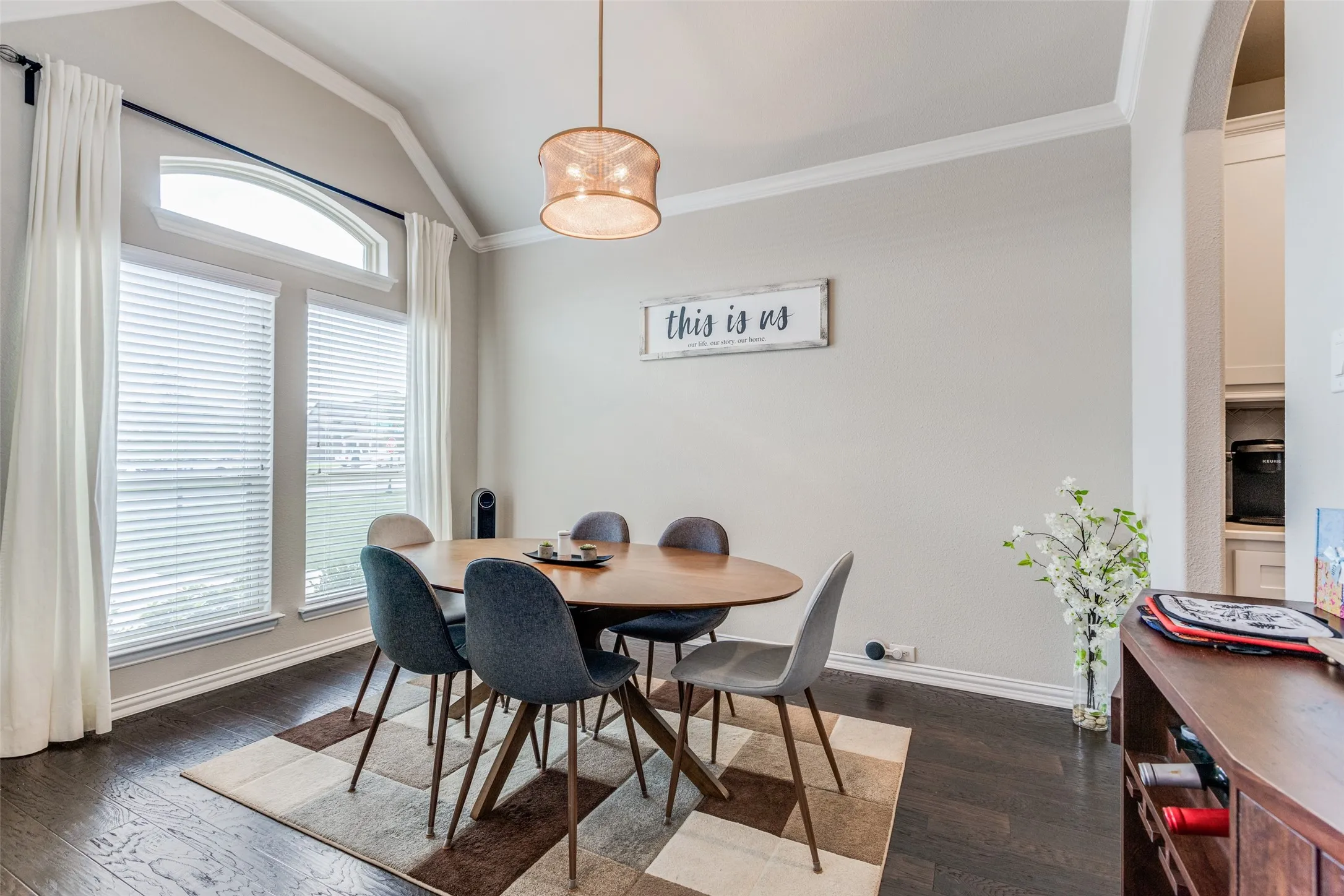 Vaulted ceiling with crown molding, wood-finish flooring, and large windows with arched transom