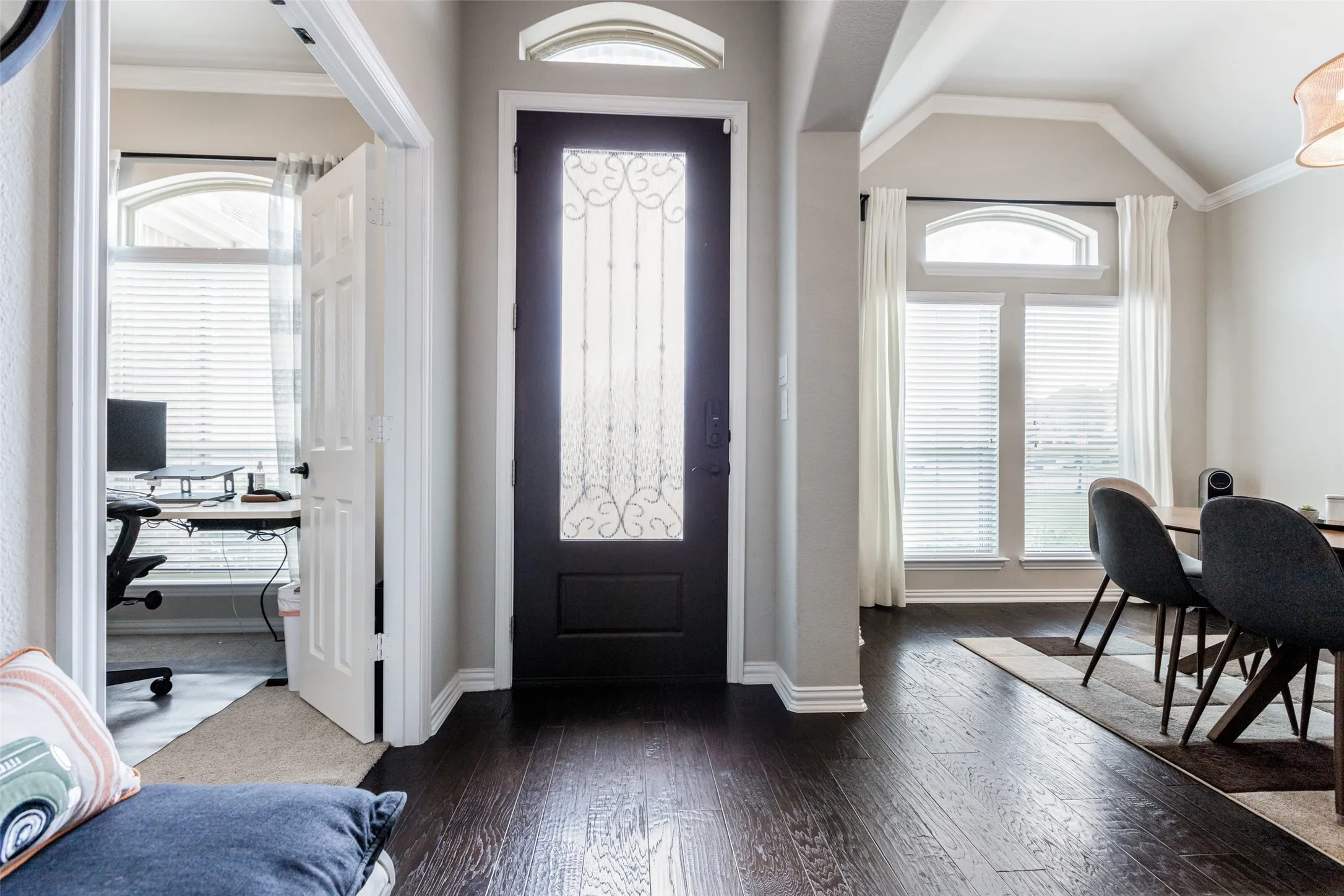 Dark wood-finish flooring throughout, decorative glass entry door with an arched transom, and vaulted ceiling details