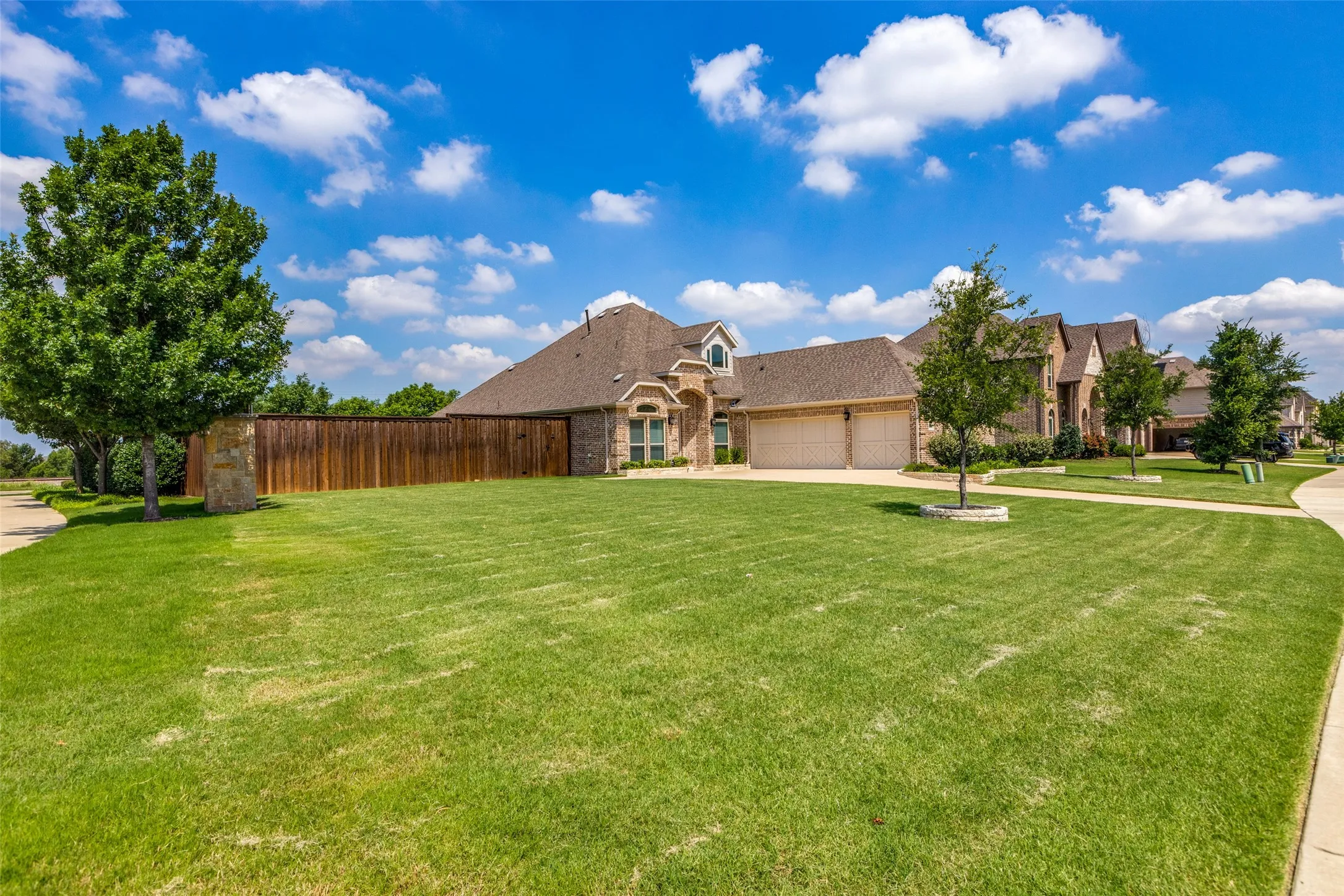 Expansive front lawn with mature trees and a paved walkway