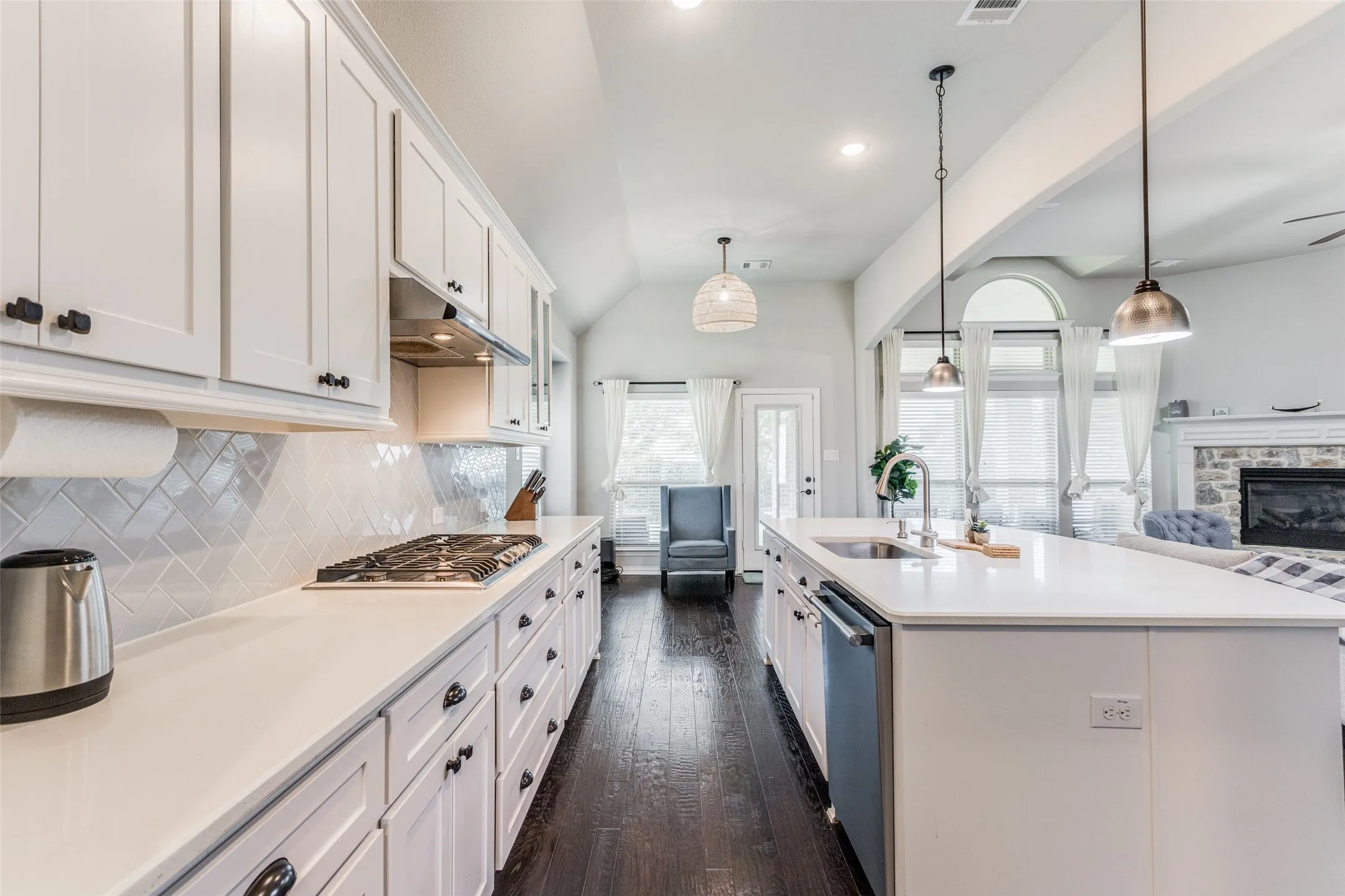 Kitchen featuring white cabinetry, light-toned countertops, a gas range, and a central island with an undermount sink