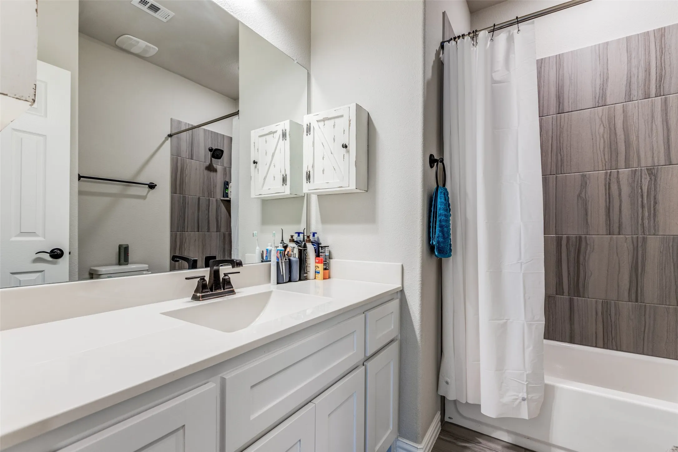Vanity with an integrated sink and bronze-finish faucet, rectangular mirror, and white cabinetry