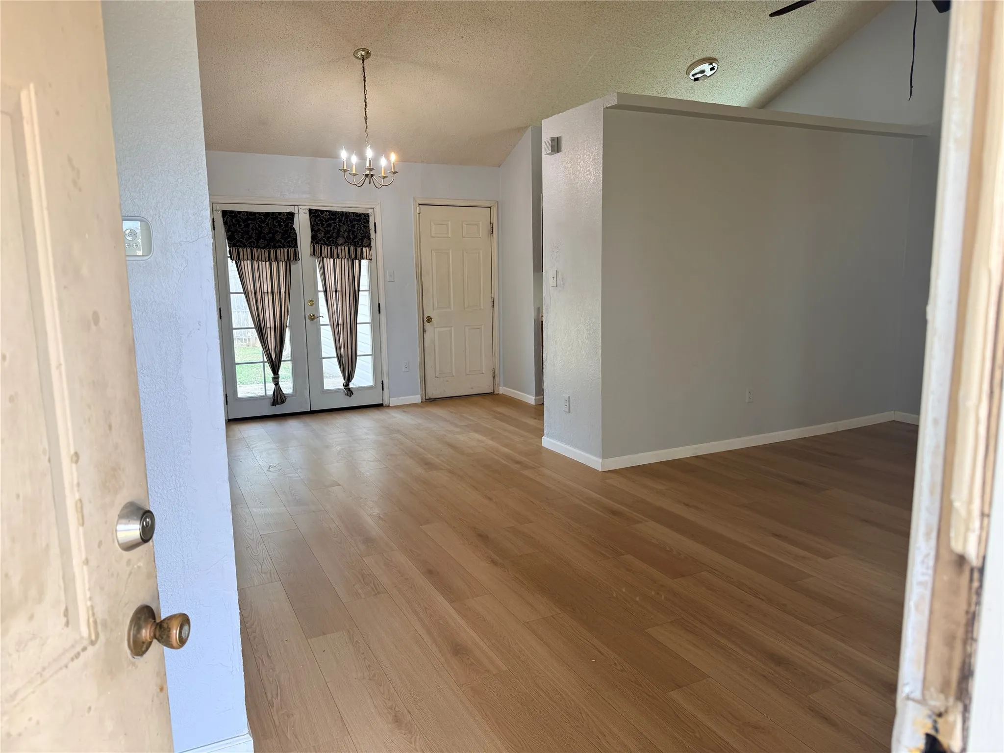 Wood-finish flooring throughout, vaulted ceiling, and a chandelier lighting fixture