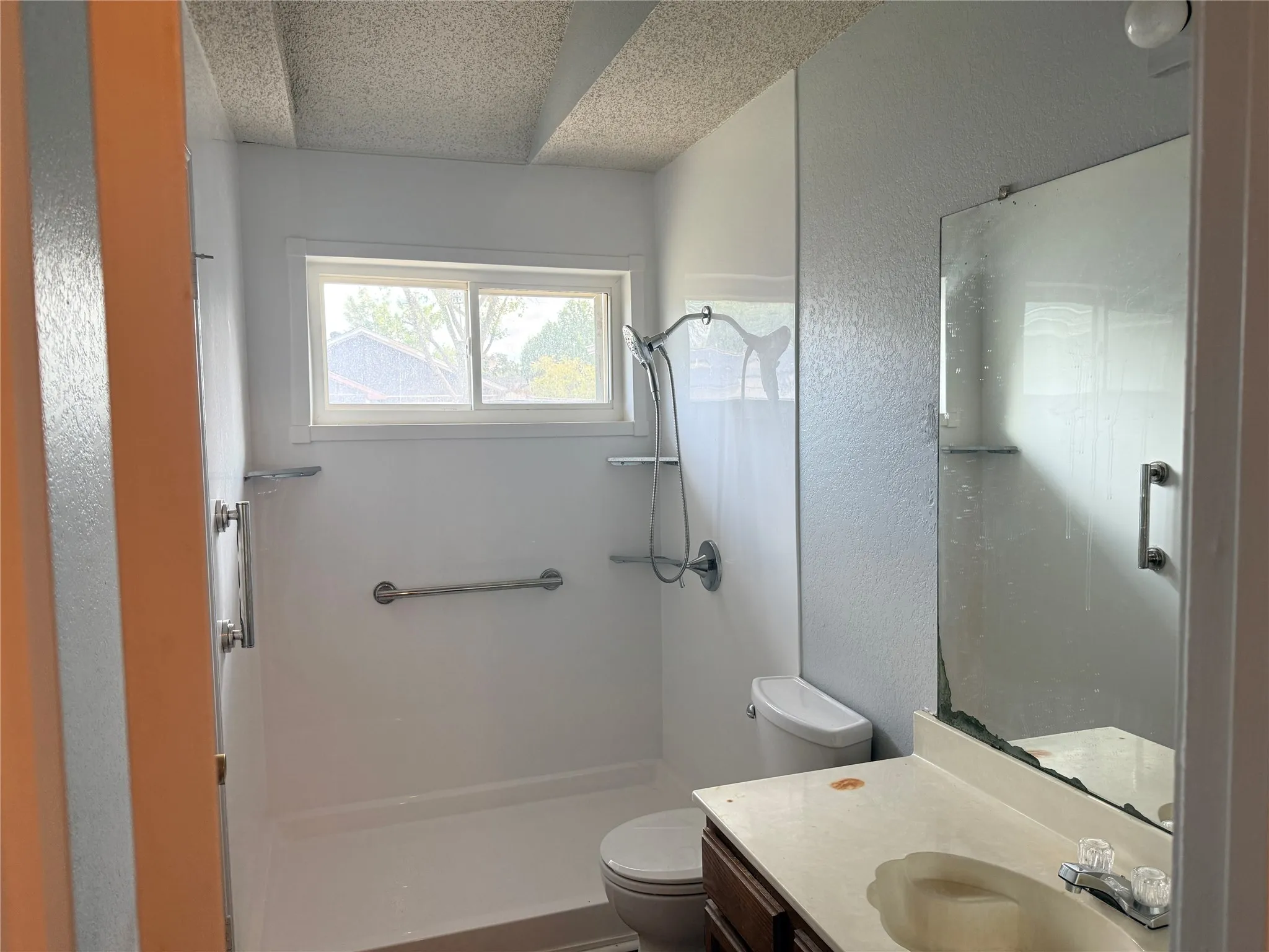 Shower with chrome fixtures, window, and grab bars