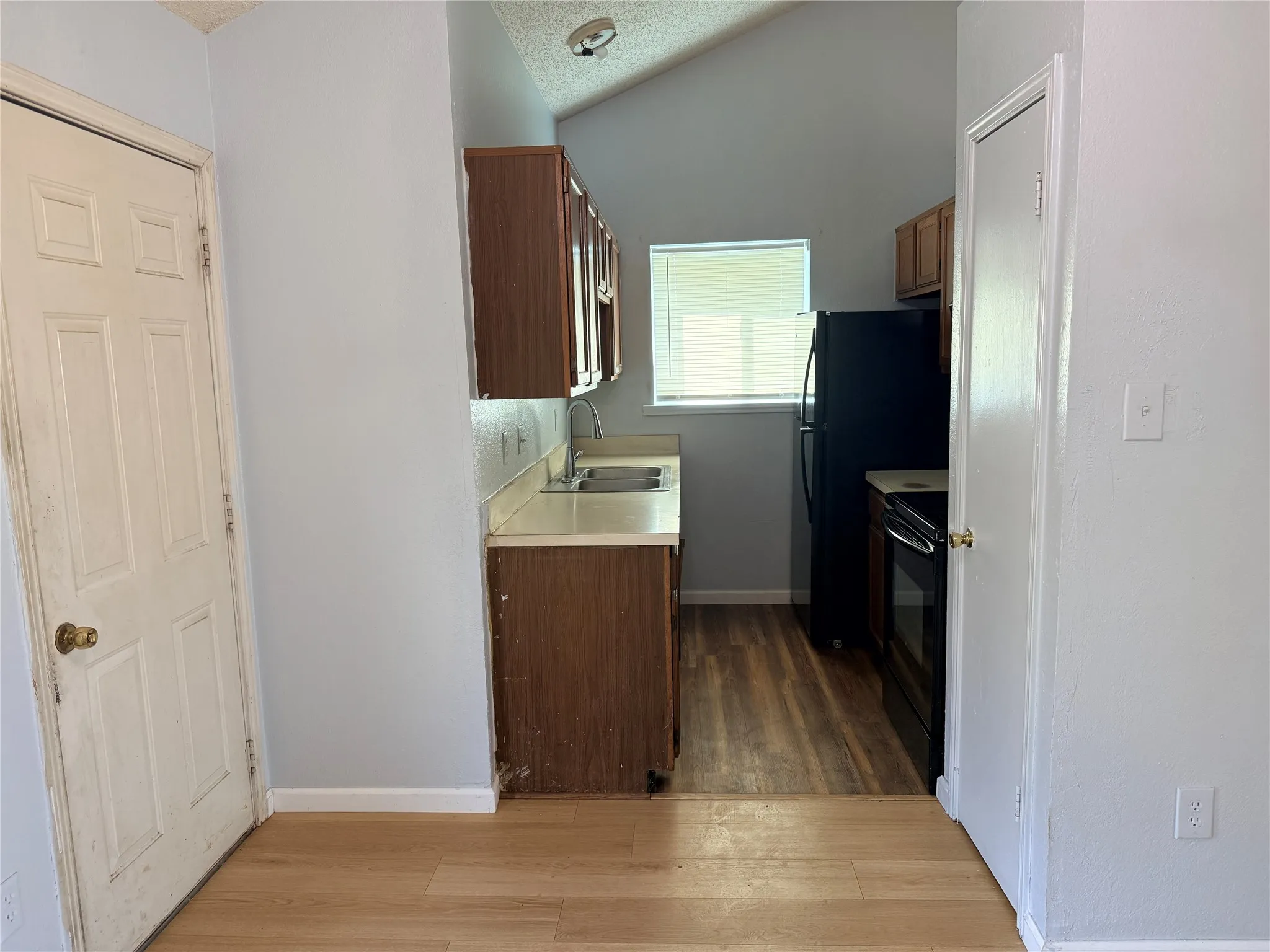 Kitchenette with wood-finish flooring, vaulted ceiling, and built-in cabinetry