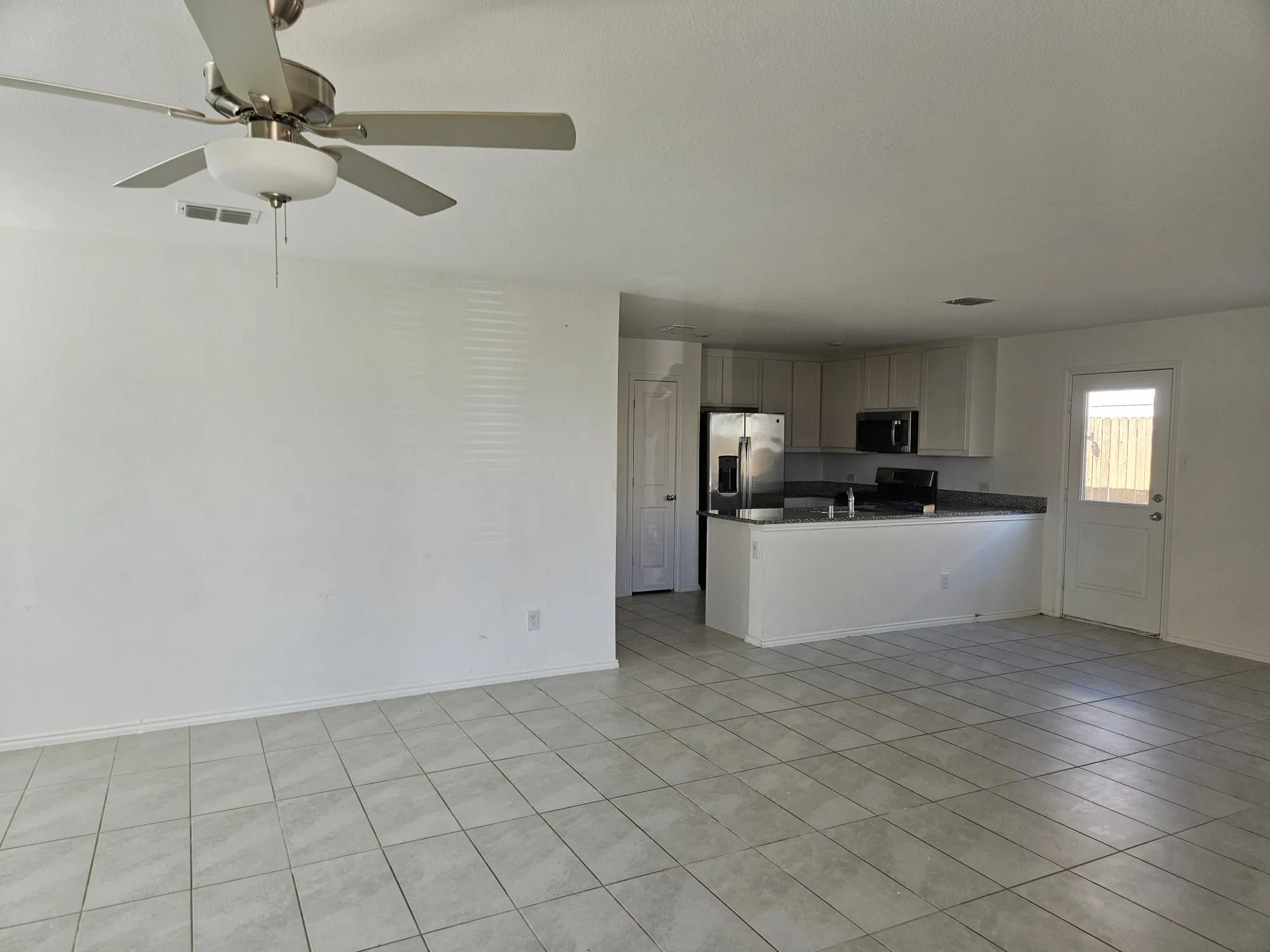 Open-concept living space with tile flooring, stainless steel appliances, and a ceiling fan