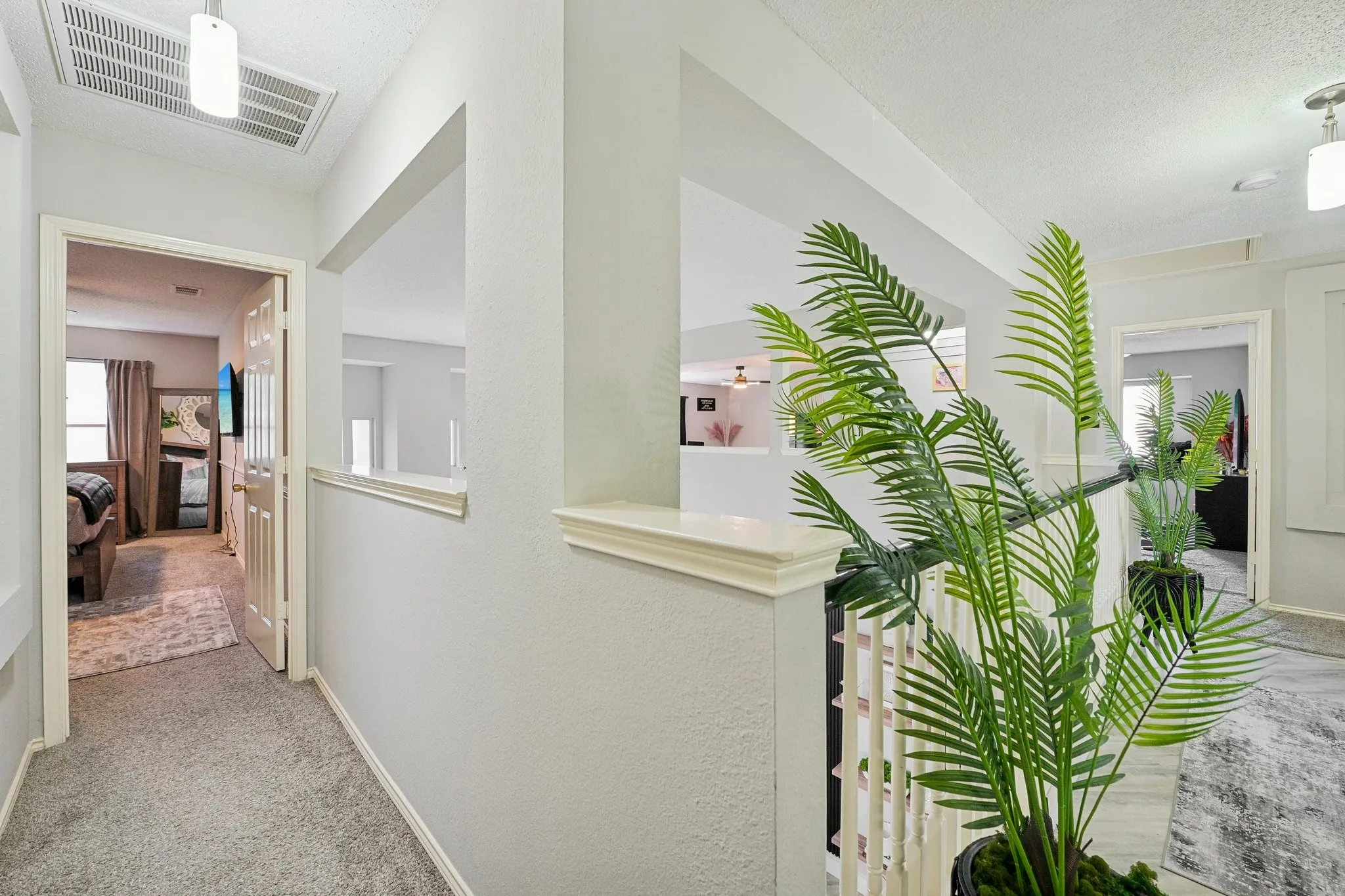 Carpeted hallway featuring a white paneled door, built-in wall shelf, and open railing