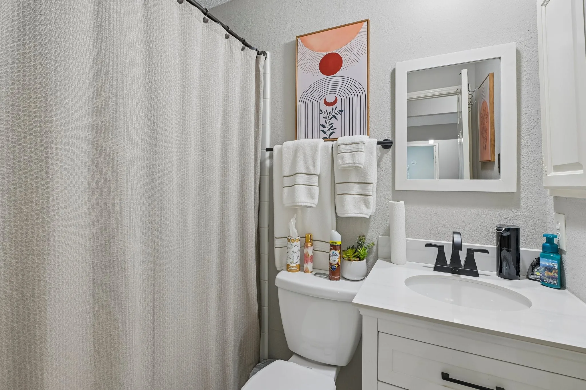 White vanity with a single basin sink, matte black faucet, and white countertop