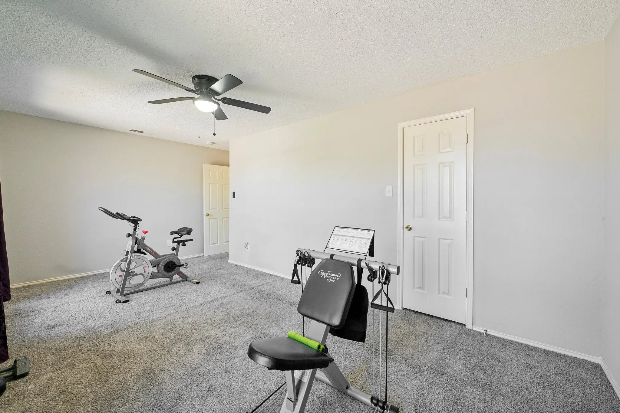 Carpeted room with a ceiling fan