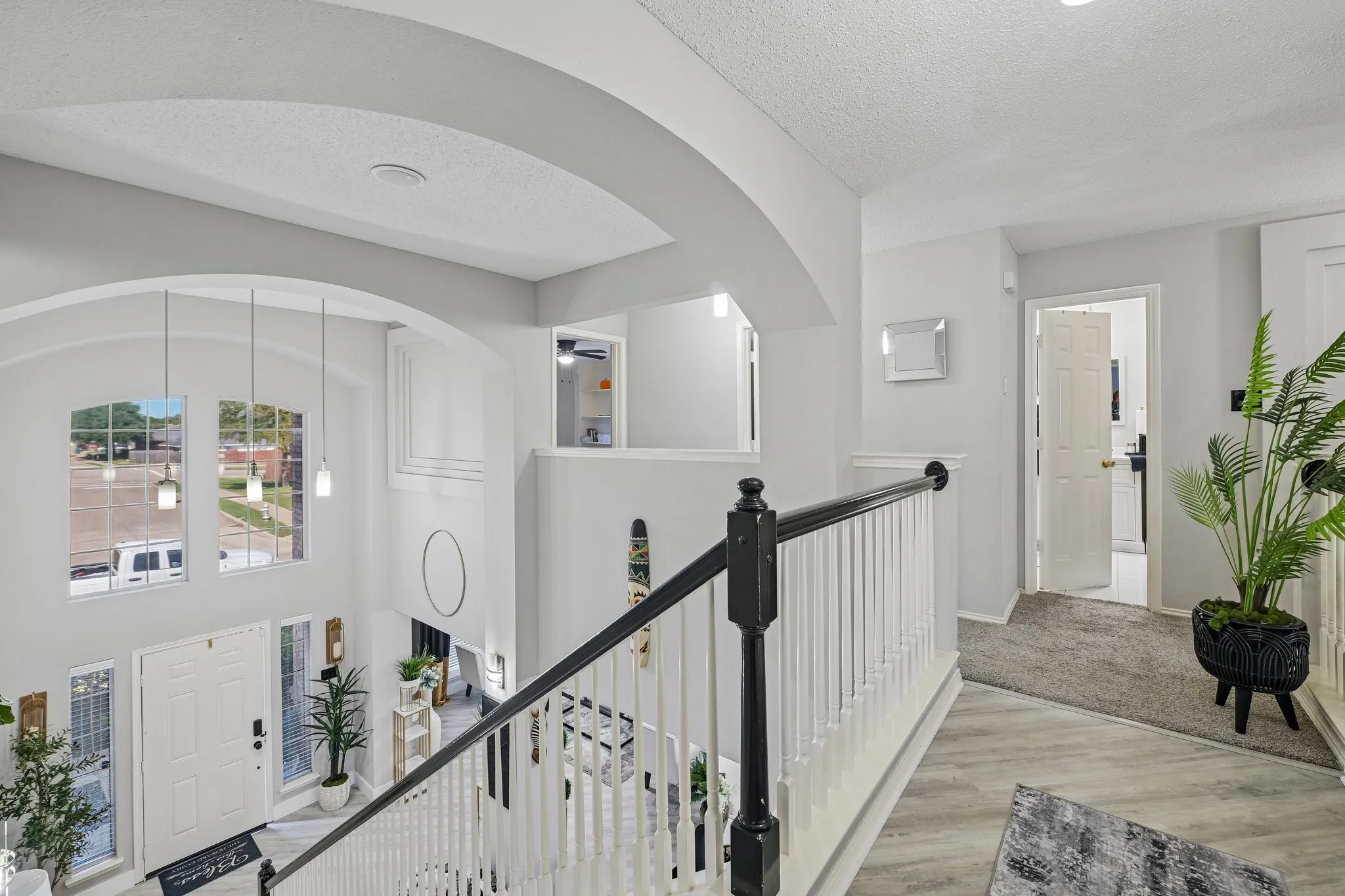 Two-story entryway with arched windows, pendant lighting, and a white paneled door