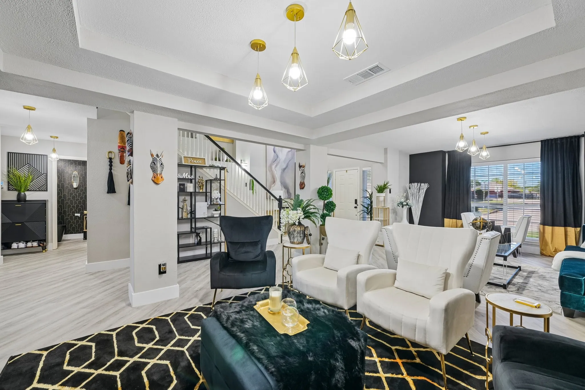 Recessed lighting, wood-finish flooring, staircase with dark handrail, tray ceiling, and modern pendant light fixtures