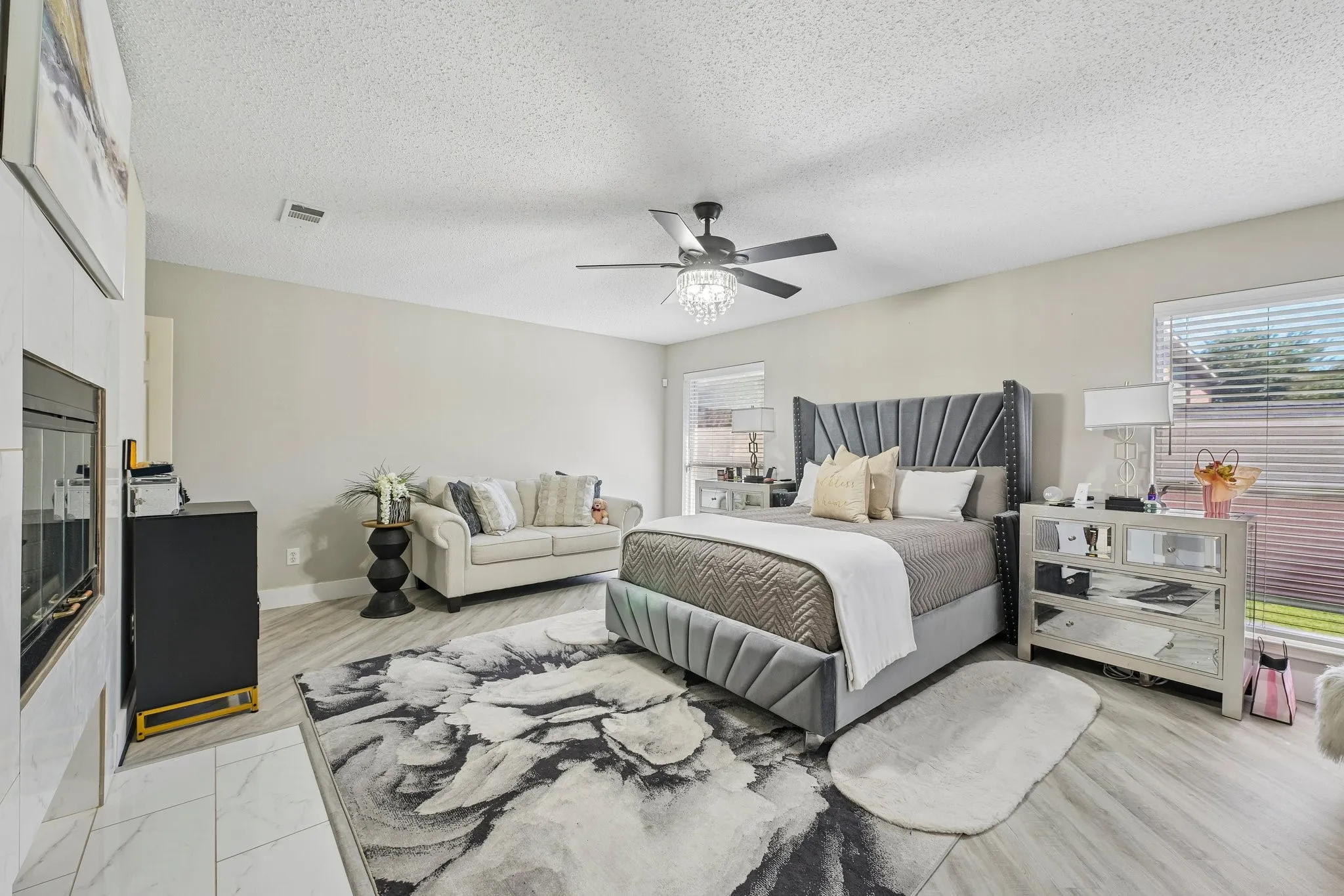 Contemporary fireplace with a tile surround, wood-finish flooring, and a ceiling fan with integrated lighting