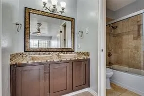 Dual vessel sinks, dark wood-finish vanity, decorative framed mirror, integrated tub with shower, and tile surround