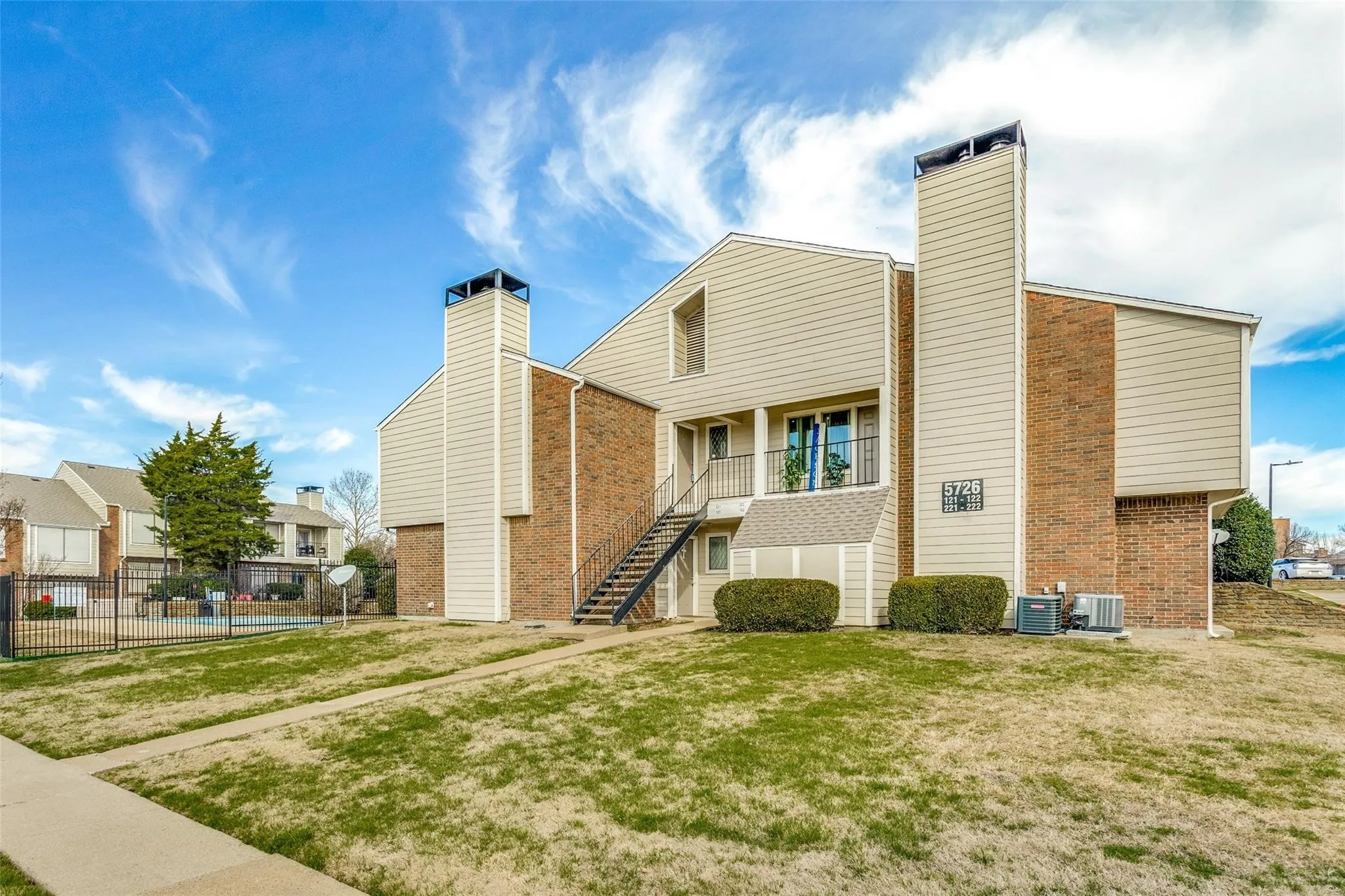 Two-story building featuring brick and siding exterior, exterior metal staircase, and an upper-level balcony with metal railing