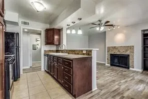 Kitchen featuring wood-finish cabinetry, tile flooring, and a breakfast bar with stone-finish countertops