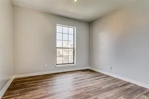 Wood-finish flooring, white wall paint, window with grid panes, and crisp white trim