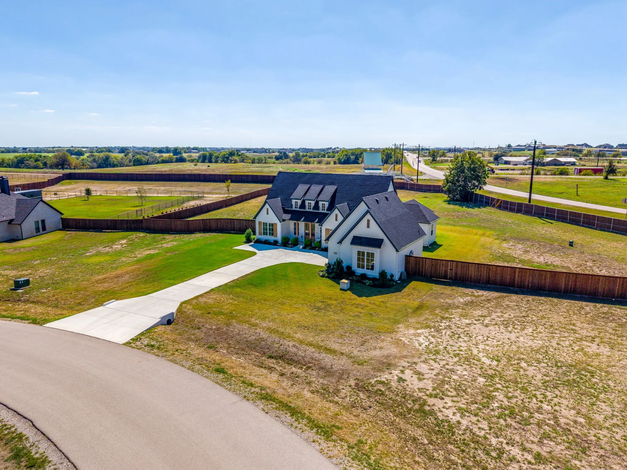 Contemporary-style residence featuring a dark shingle roof, white exterior, and a well-defined concrete driveway