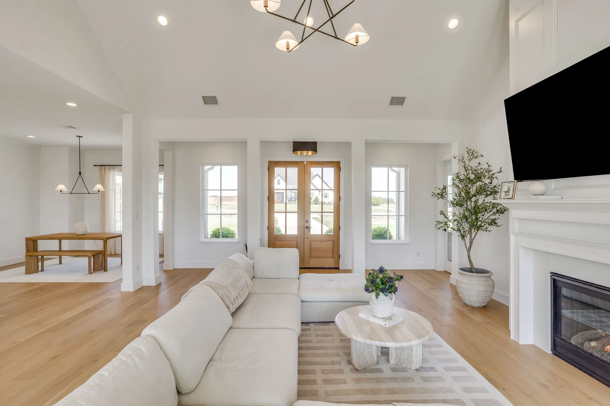 Vaulted ceiling living area with a fireplace, wood-finish flooring, and recessed lighting