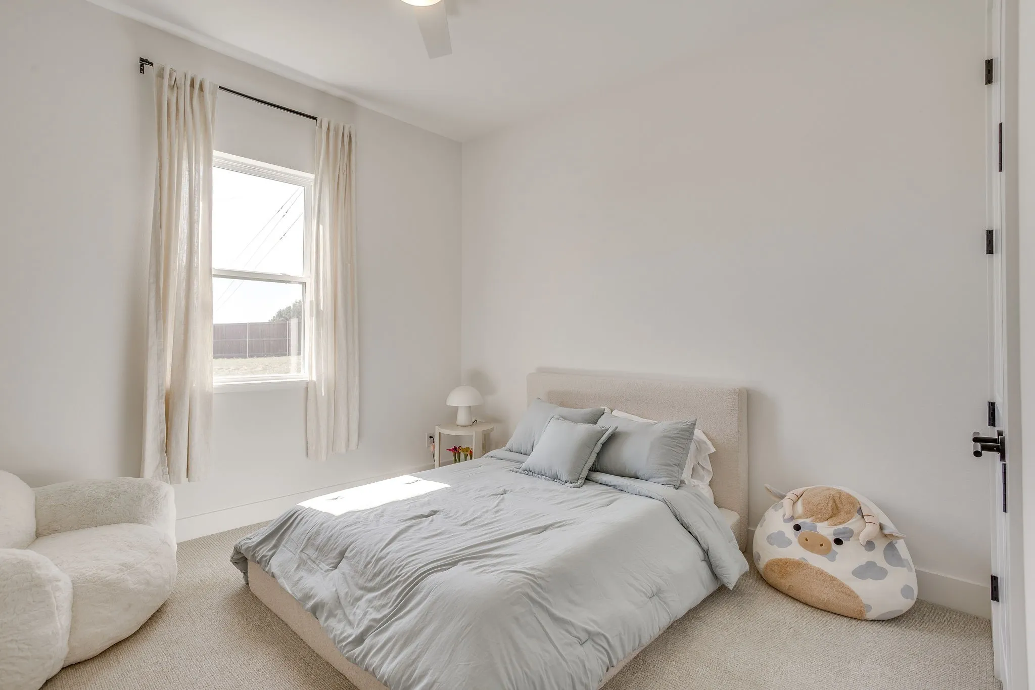 White walls, single window with roller shade, ceiling fan, and carpeted flooring