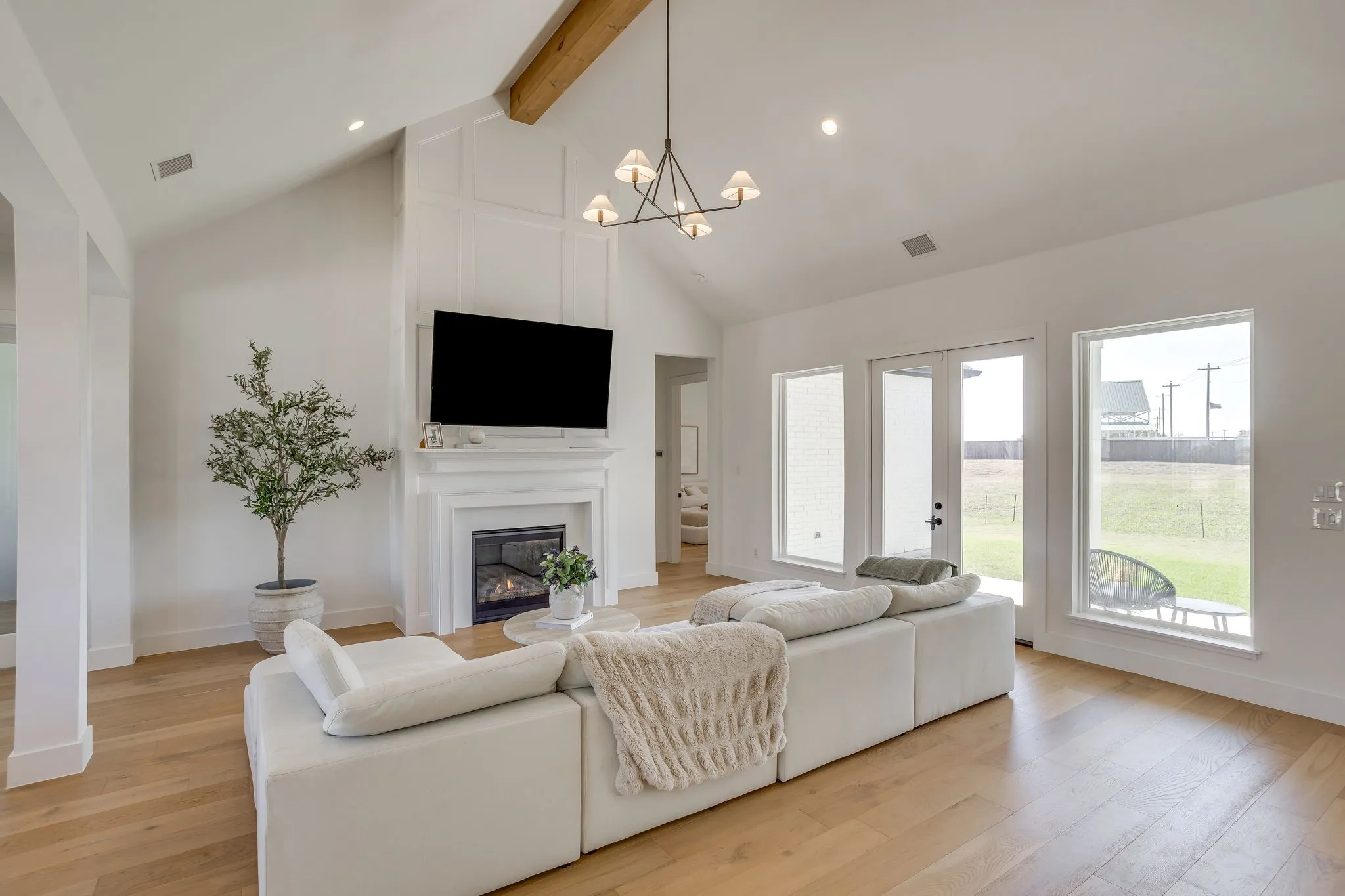 Vaulted ceiling with exposed wood beam, recessed lighting, and a contemporary chandelier