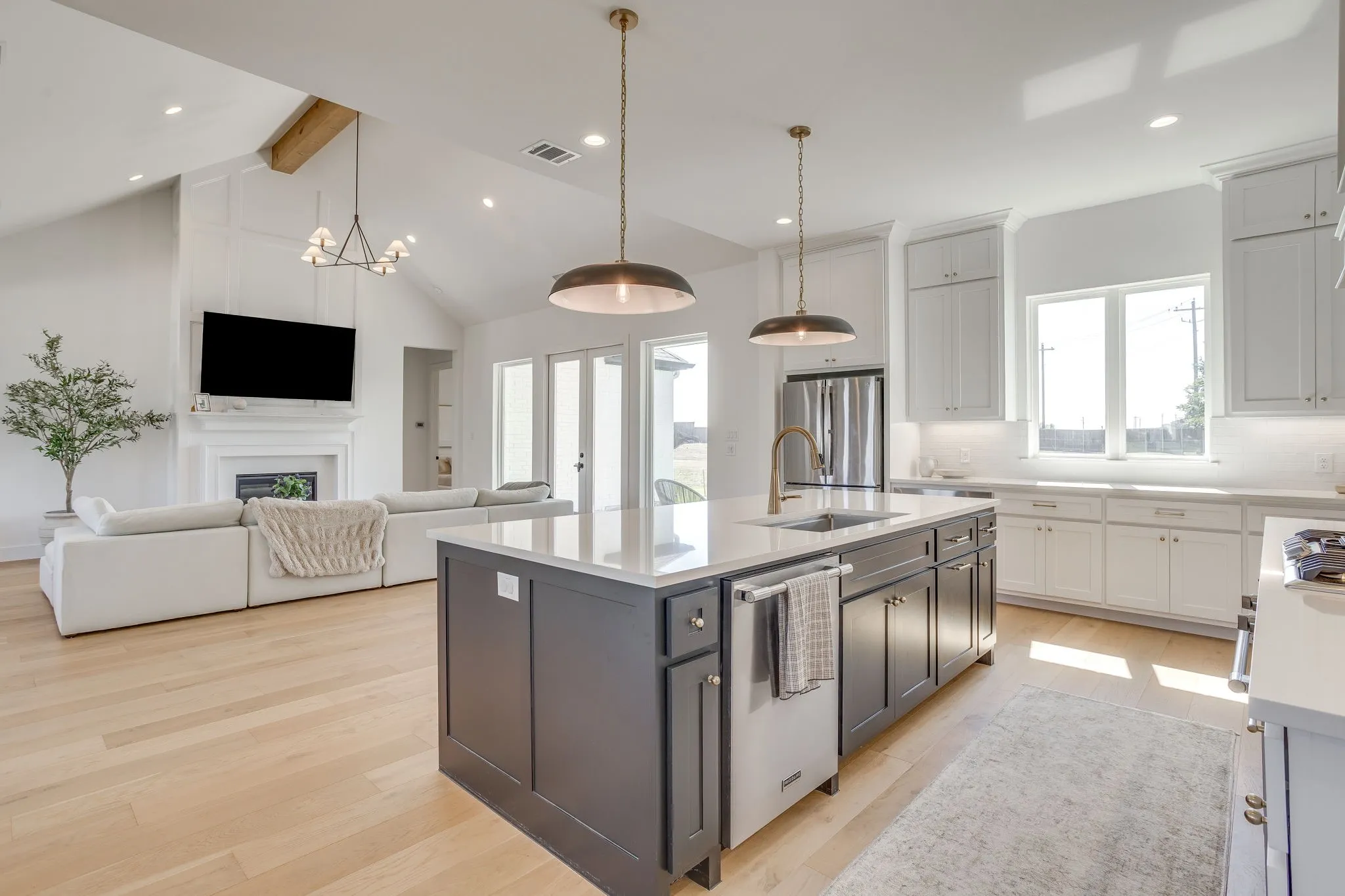 Kitchen featuring a central island with integrated sink, stainless steel appliances, pendant lighting, and light wood-finish flooring