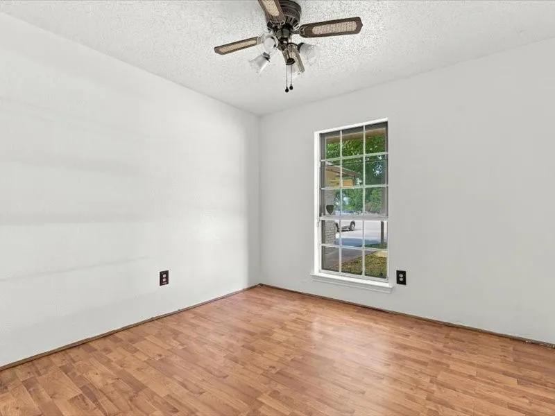 Wood-finish flooring, single window, textured ceiling, and a ceiling fan with light fixture