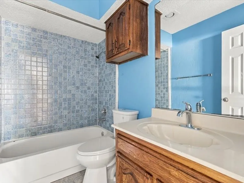 Bathroom featuring a tub and shower combination with tiled surround, a vanity with an integrated sink and chrome faucet, and a wall-mounted medicine cabinet