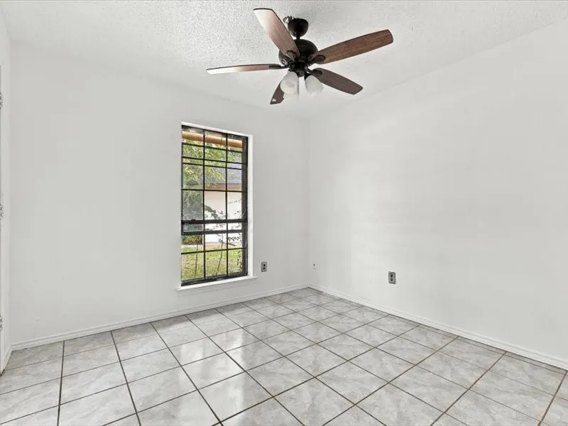Tile flooring, white walls, black-framed window, and a ceiling fan with light fixture