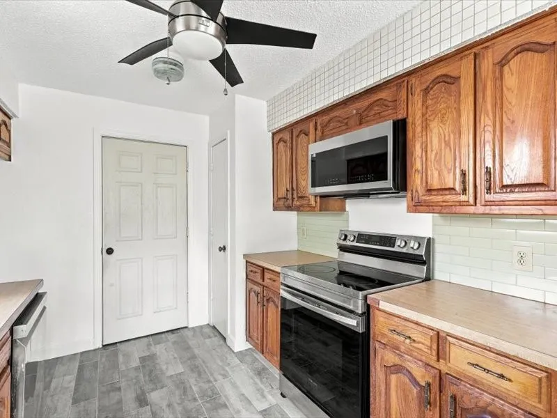 Kitchen featuring wood cabinetry, stainless steel appliances, light-toned countertops, and tile flooring