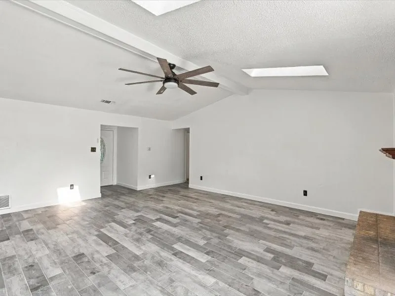 Vaulted ceiling, wood-finish flooring, ceiling fan, skylight, fireplace