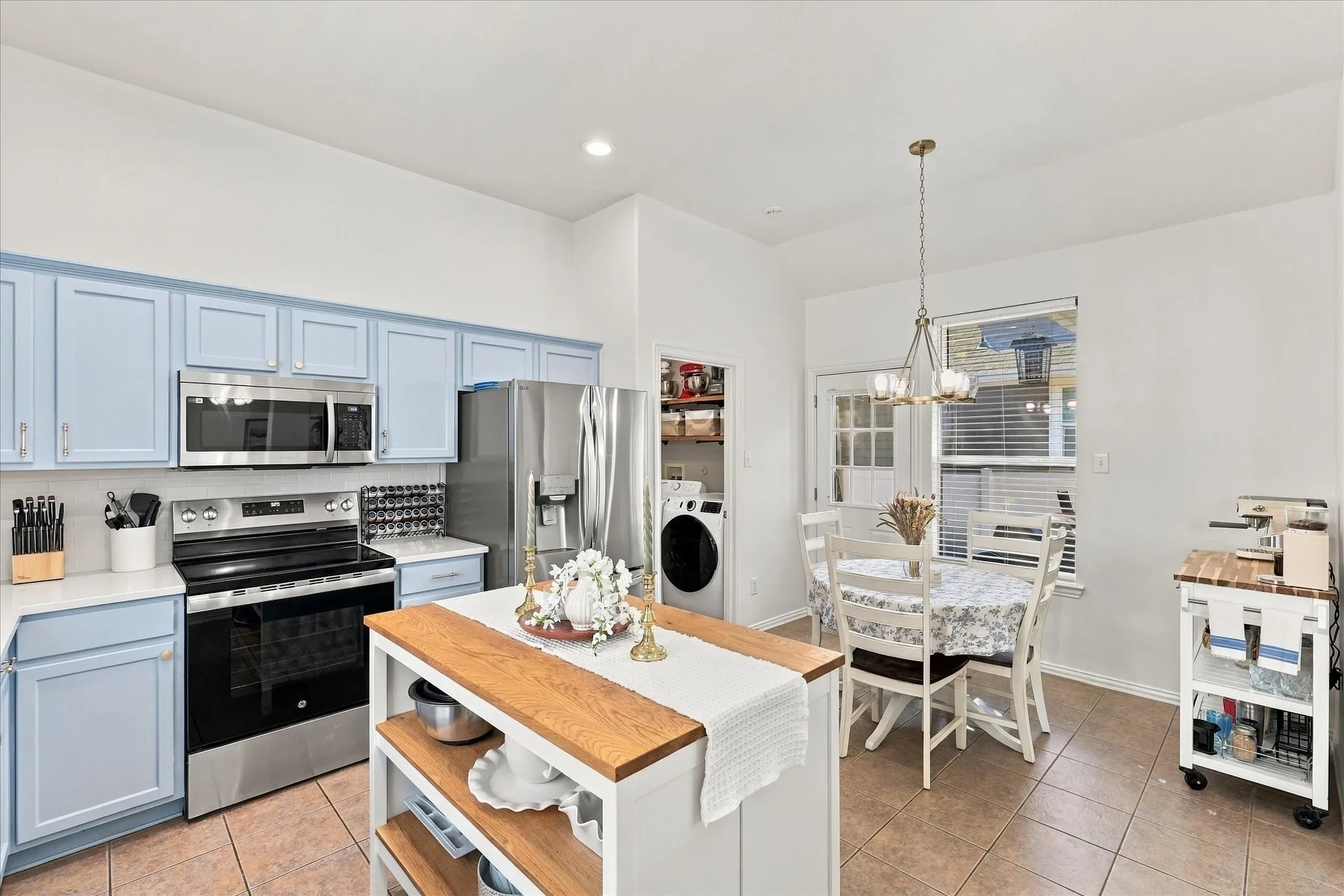 Kitchen featuring light blue cabinetry, stainless steel appliances, a center island with a wood countertop, and tile flooring