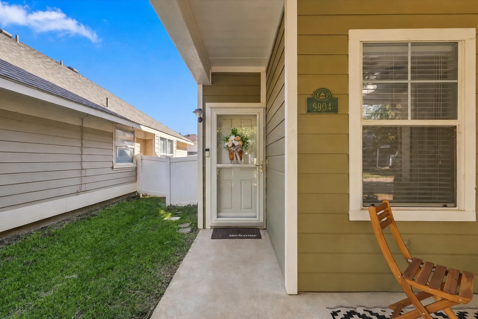 Green siding exterior with white trim, a covered porch, and a concrete pathway