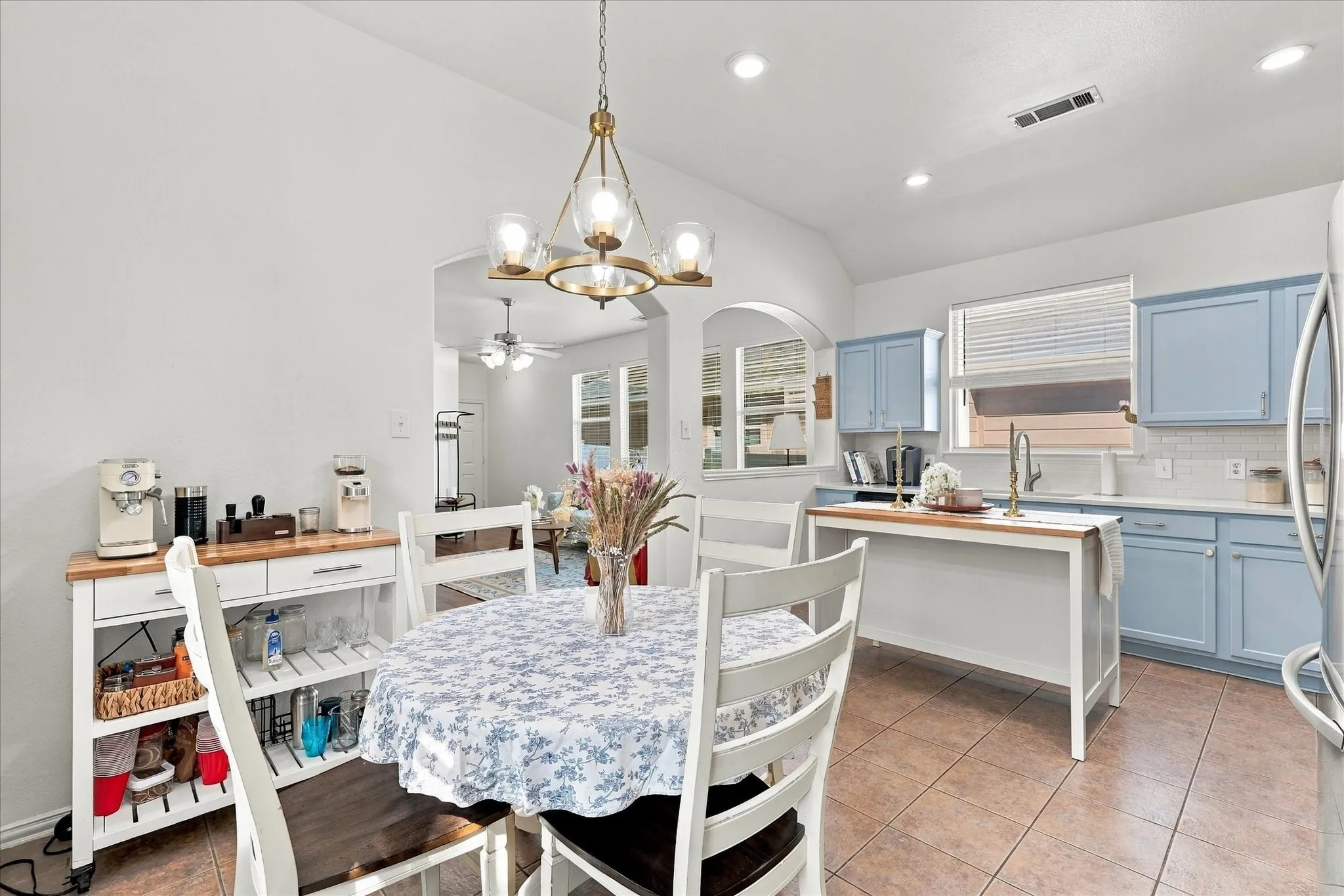 Kitchen featuring light blue cabinetry, white subway tile backsplash, and a gold-toned chandelier
