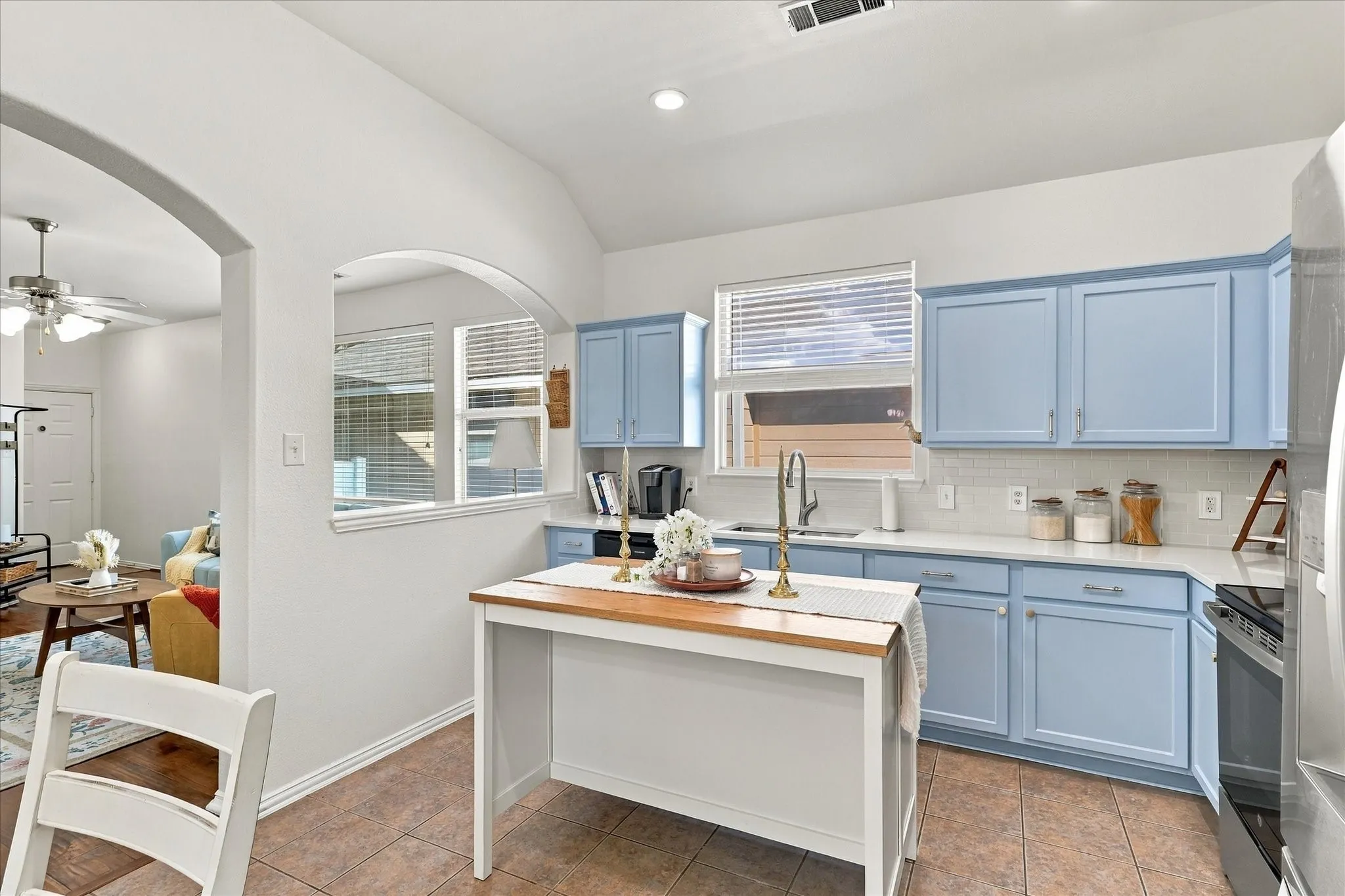 Kitchen featuring light blue cabinetry, white countertops, white subway tile backsplash, and a central island with a wood-finish top