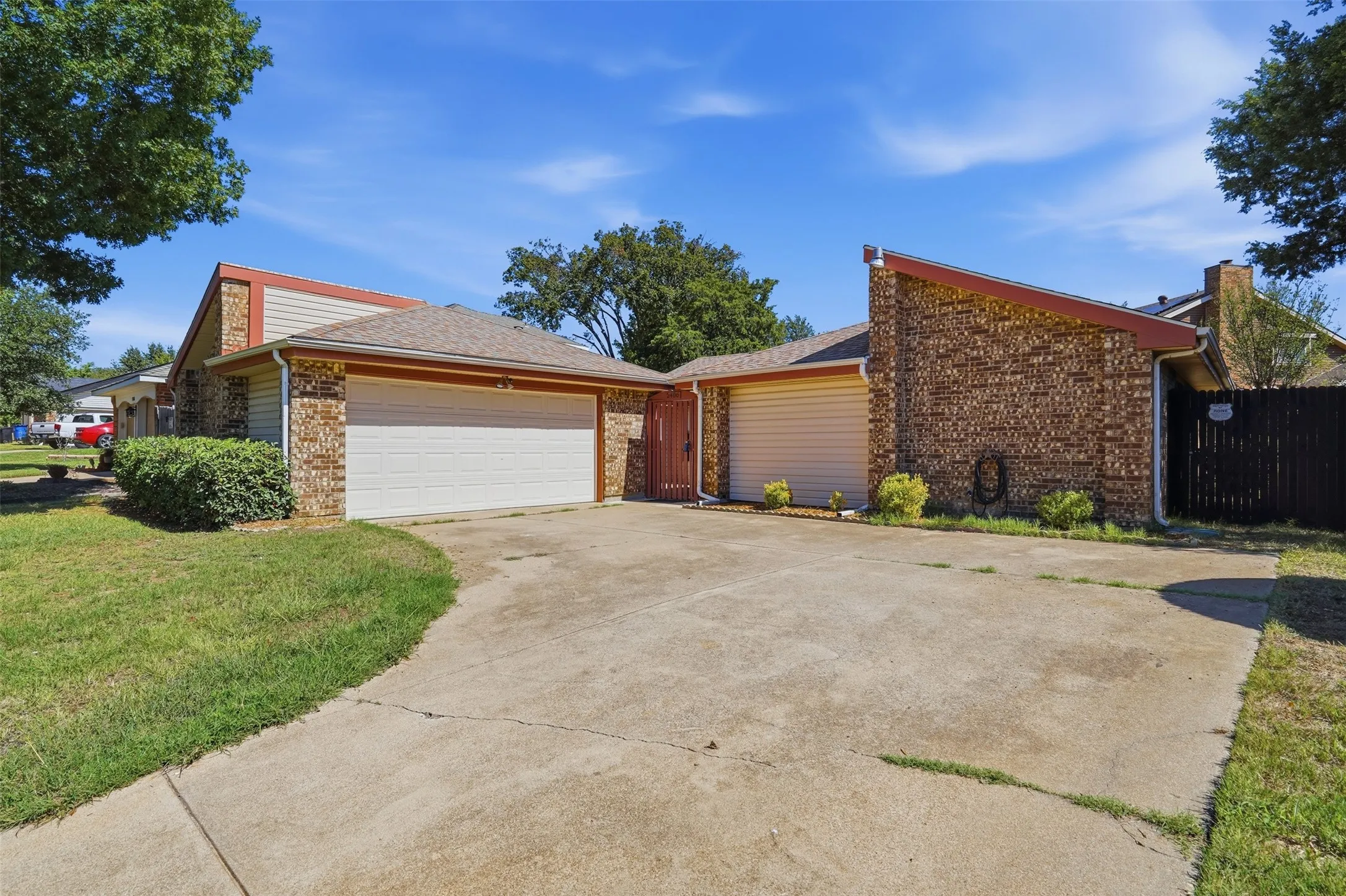 Brick exterior with two garage doors and an attached privacy fence