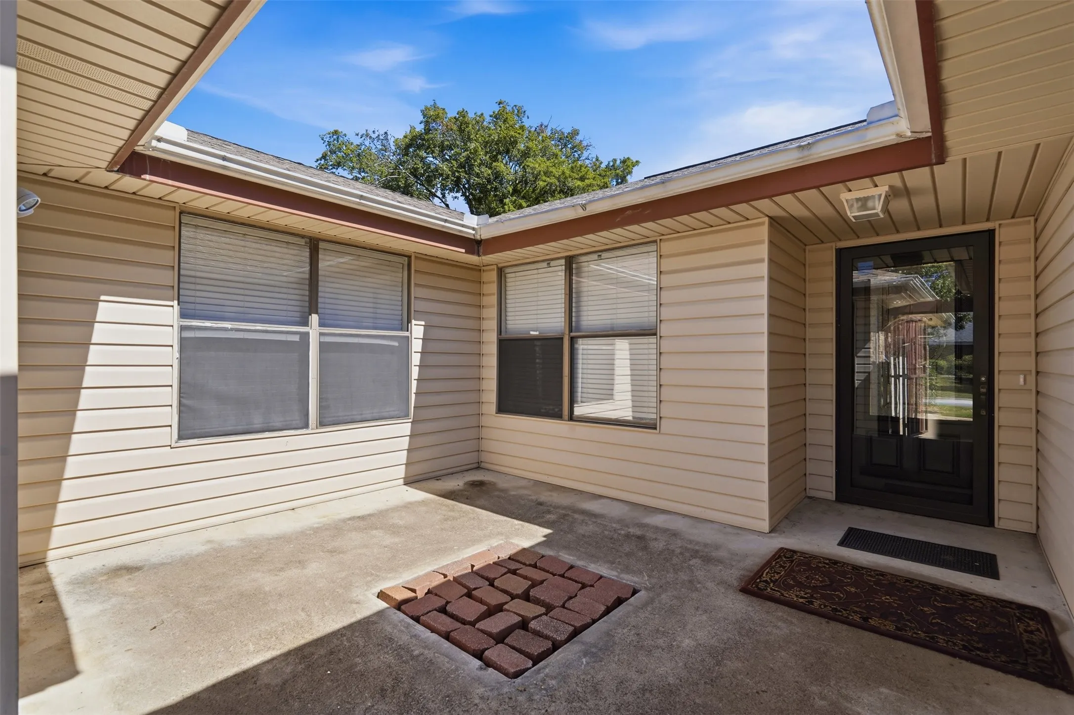 Recessed entryway with concrete flooring, accented by a square paver insert
