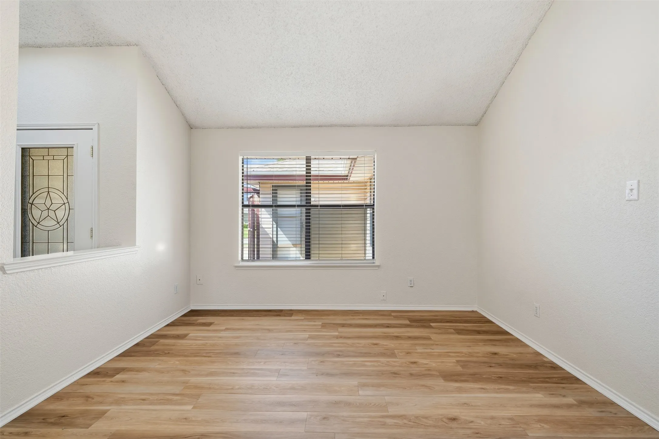 Wood-finish flooring, white walls, and a window with horizontal blinds