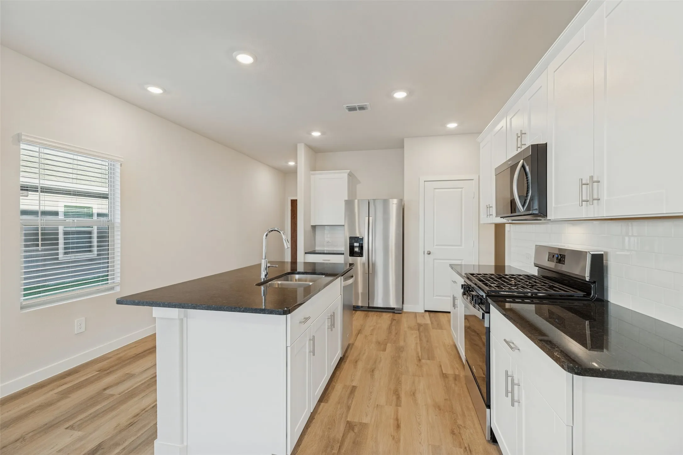 Made for Cooking & Conversation! - The stainless steel gas range, built-in microwave, and easy-care tile backsplash create a practical cooking area, while the generous granite countertops and nearby island make meal preparation and gathering effortless.