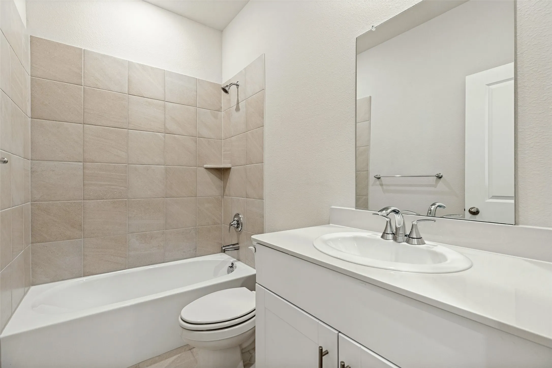 Fresh Finishes & Everyday Functionality! - The secondary bathroom features a white vanity with chrome fixtures, a spacious mirror, and a tub-shower combination with ceramic tile surround, offering a clean, contemporary look and practical convenience.
