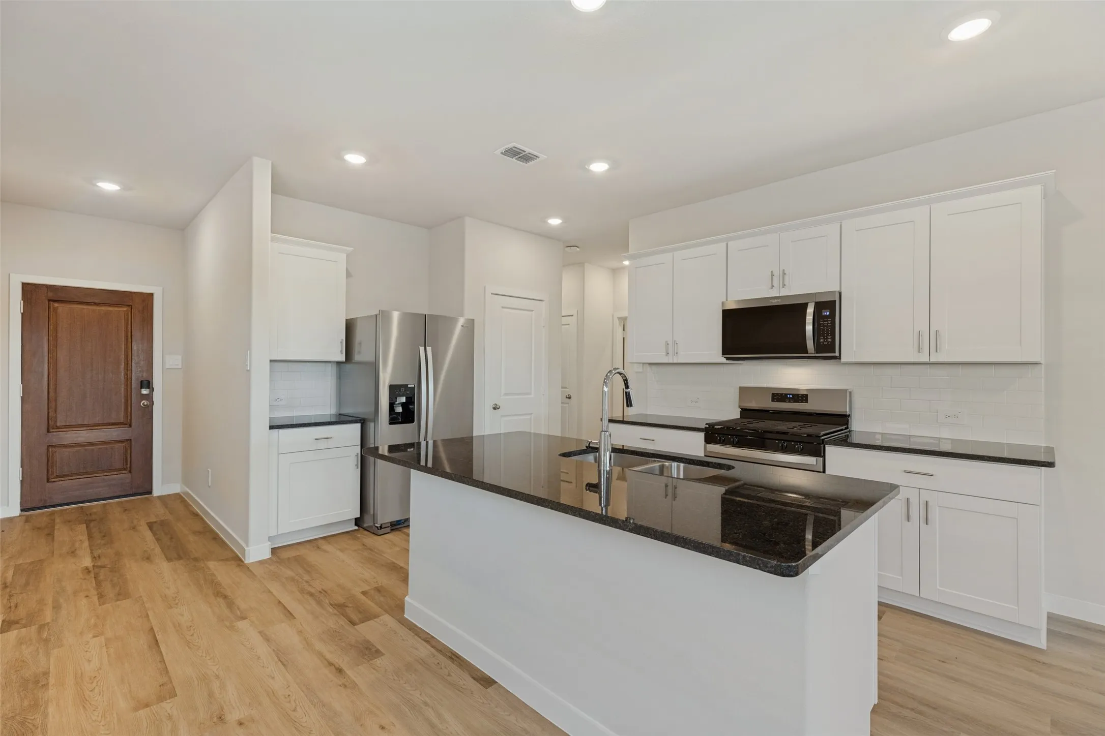 Everything You Need, Right Where You Need It! - Enjoy generous cabinet storage, expansive countertop space, and a thoughtfully arranged kitchen featuring a stainless steel refrigerator, gas range, built-in microwave, and a large island with an undermount sink.
